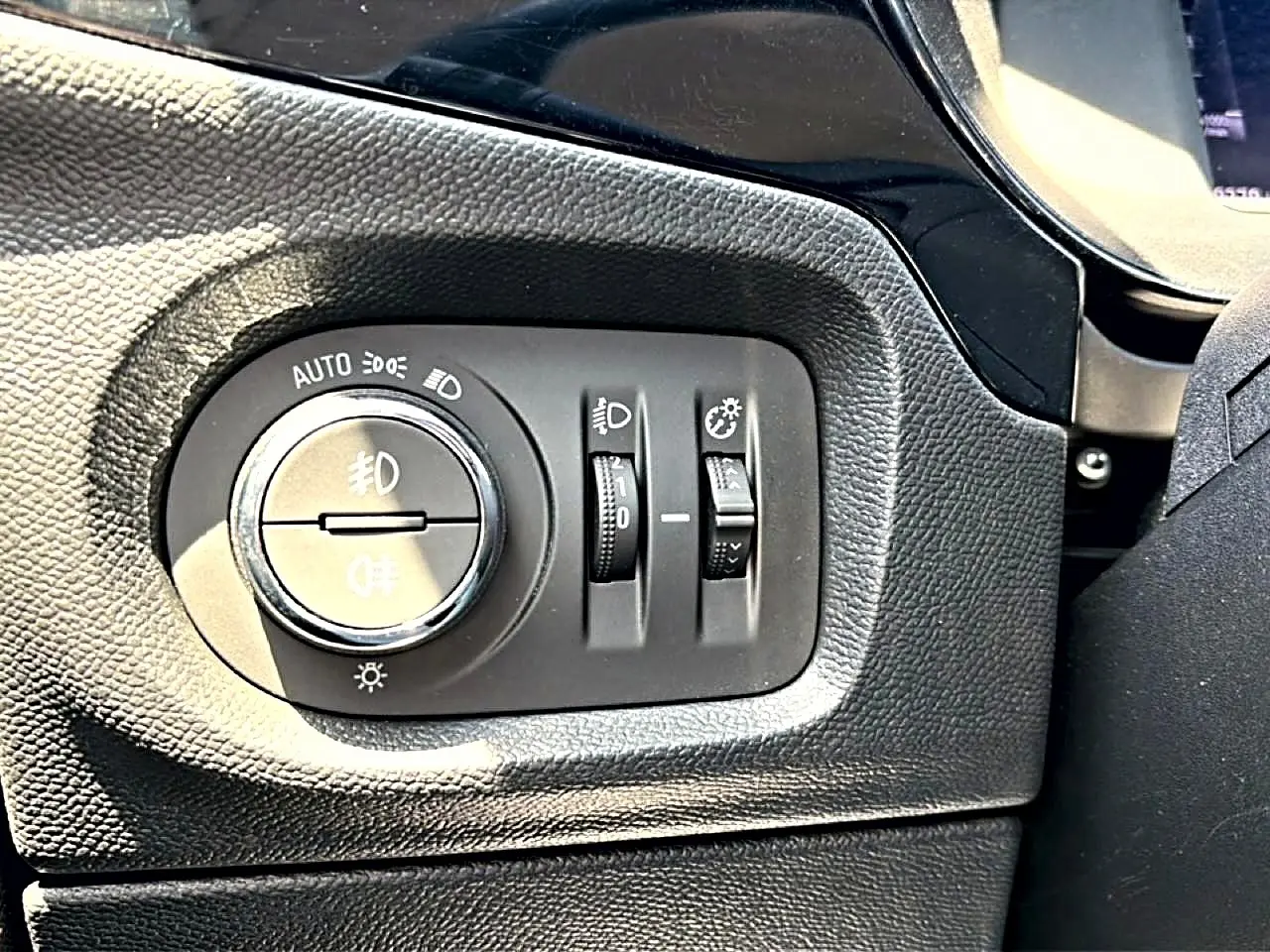 Détail du panneau de commande des phares noir à gauche du volant dans l’Opel Corsa 1.2 turbo 100 édition 2025.