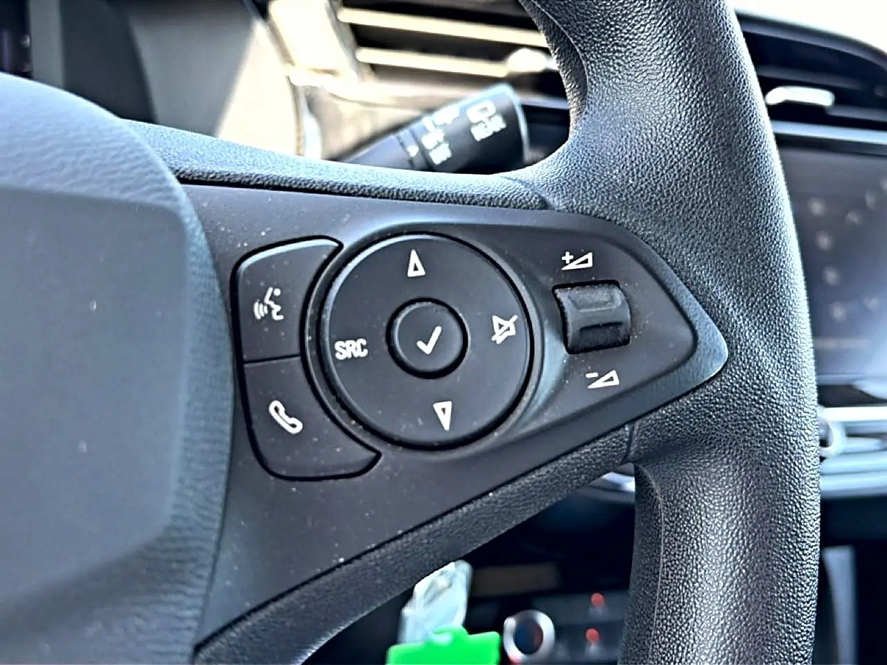 Gros plan sur les commandes audio au volant noir de l’Opel Corsa 1.2 turbo 100 edition 2025, intérieur visible flou.