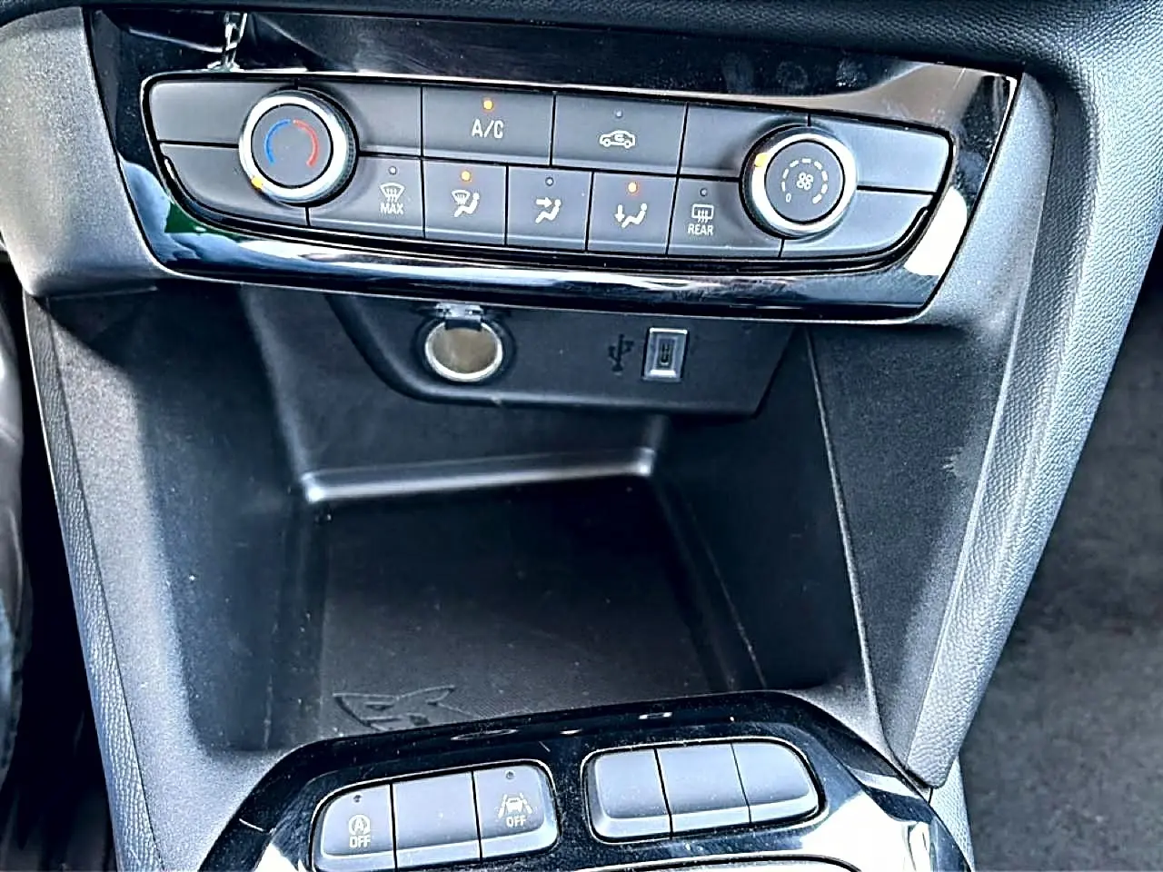Vue rapprochée de la console centrale noire de l’Opel Corsa 1.2 turbo 100 edition avec commandes clim et prises USB et 12V.