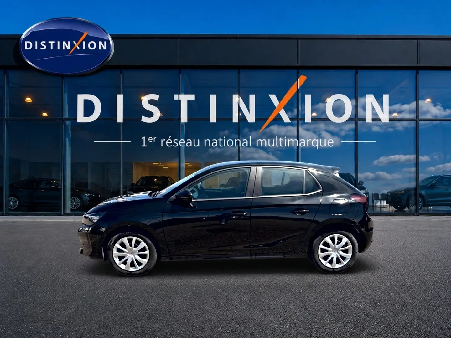 Profil droit d’une Opel Corsa 1.2 turbo 100 edition noire avec enjoliveurs blancs, stationnée devant une vitrine Distinxion.