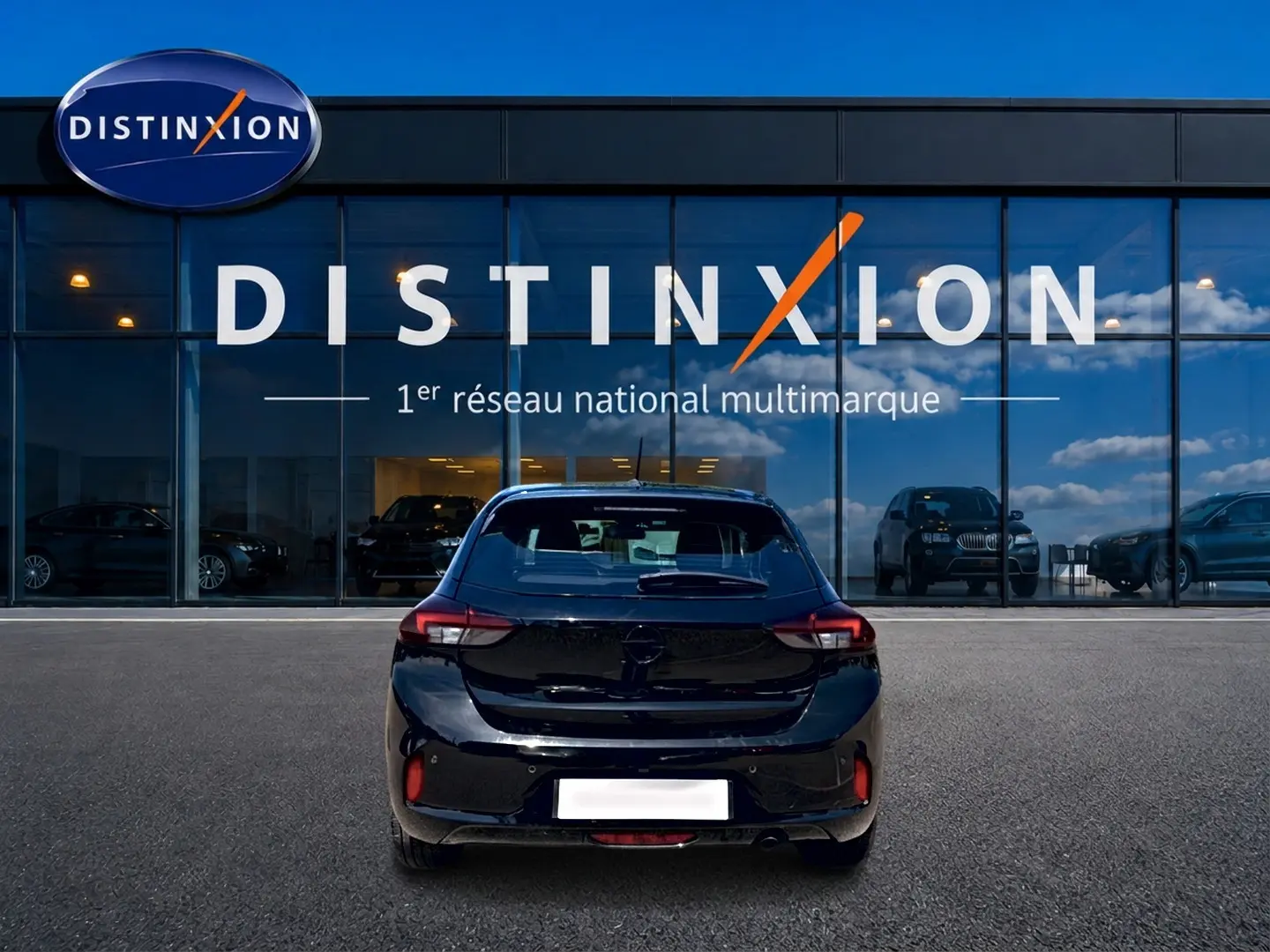 Vue arrière d'une Opel Corsa 1.2 turbo 100 édition noire, stationnée devant une vitrine avec logo Distinxion.