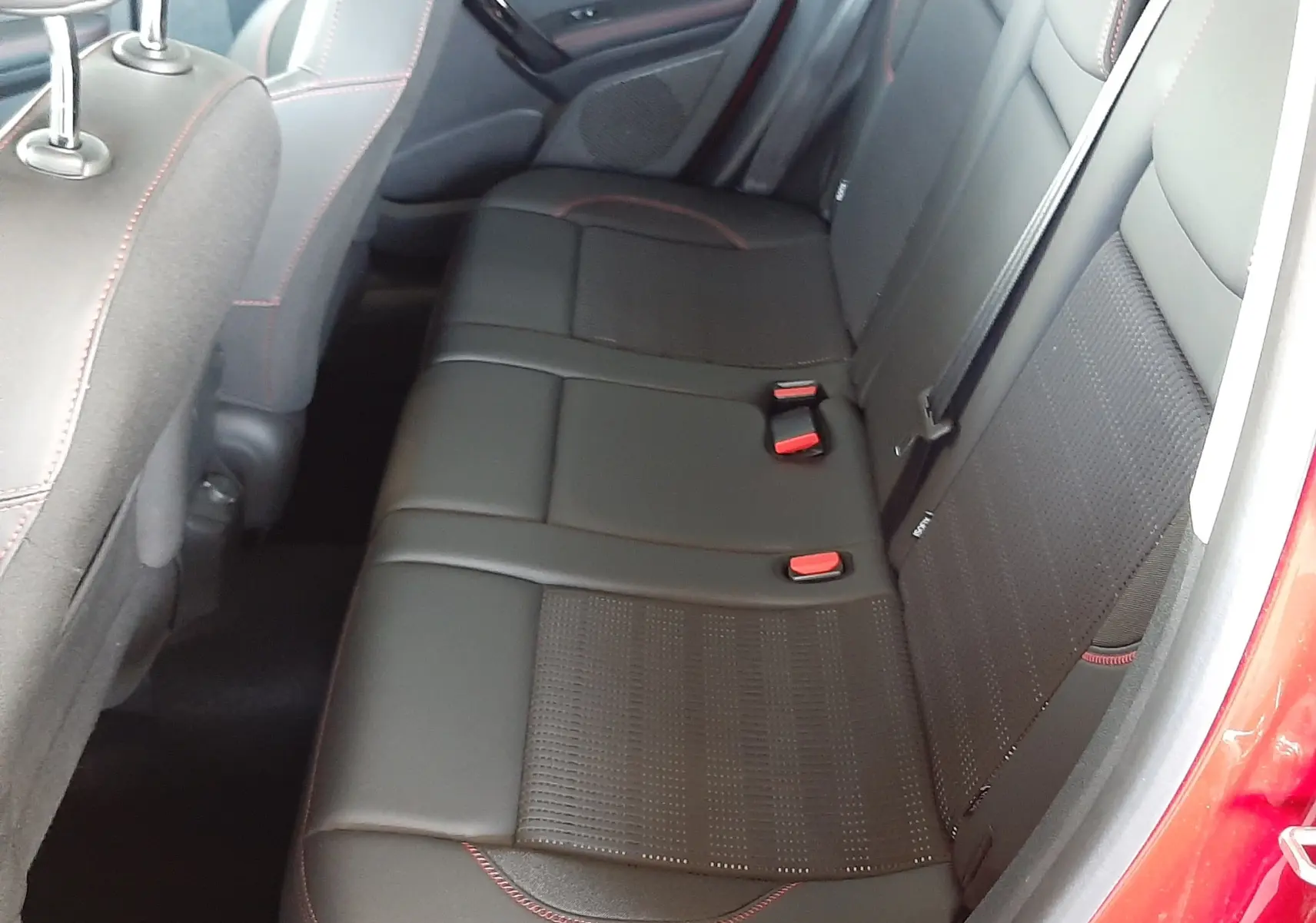 Vue intérieure côté droit des sièges arrière noirs en cuir avec surpiqûres rouges d'un Peugeot 2008 rouge Ultimate Metal de 2019.