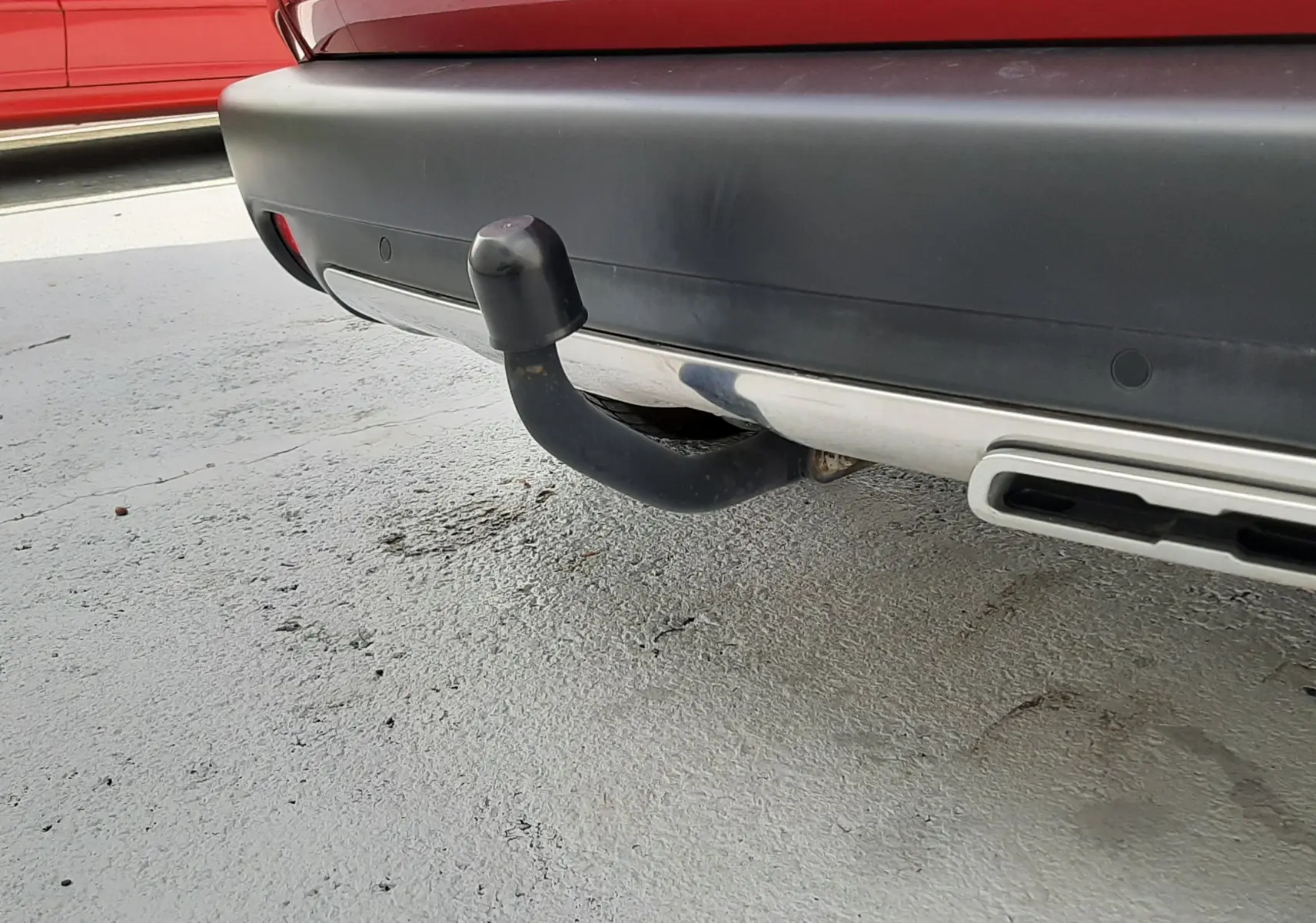 Gros plan sur l'attelage arrière noir d'un Peugeot 2008 rouge Ultimate Metal, avec pare-chocs noir et sortie d'échappement chromée.