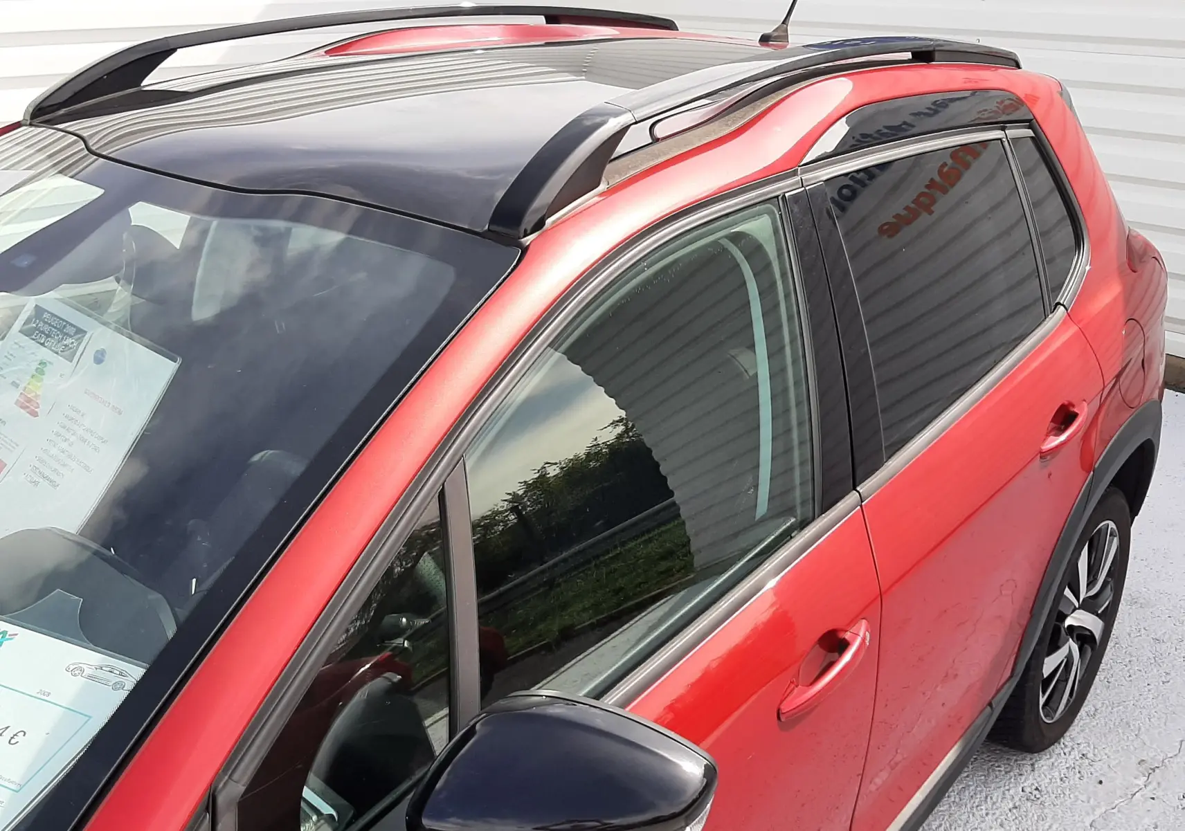 Vue 3/4 avant droit du Peugeot 2008 rouge Ultimate Metal avec toit noir brillant et rétroviseur noir.