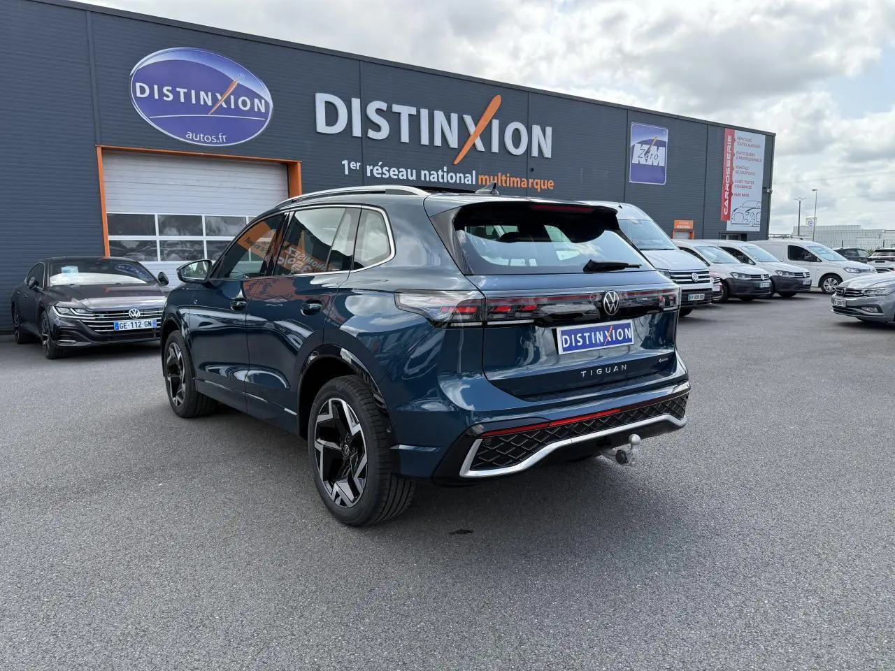 Volkswagen Tiguan 2024 bleu Nightshade vu 3/4 arrière droit avec crochet d'attelage et jantes R-Line noires.