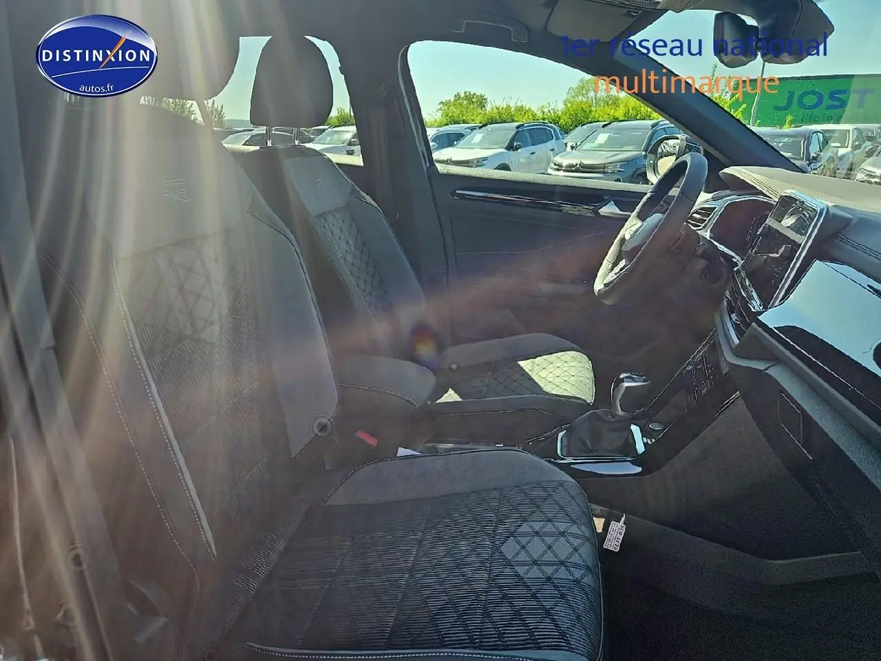 Vue intérieure côté gauche du Volkswagen T-Roc 2025, sièges tissu noir avec surpiqûres et volant cuir multifonction sport.