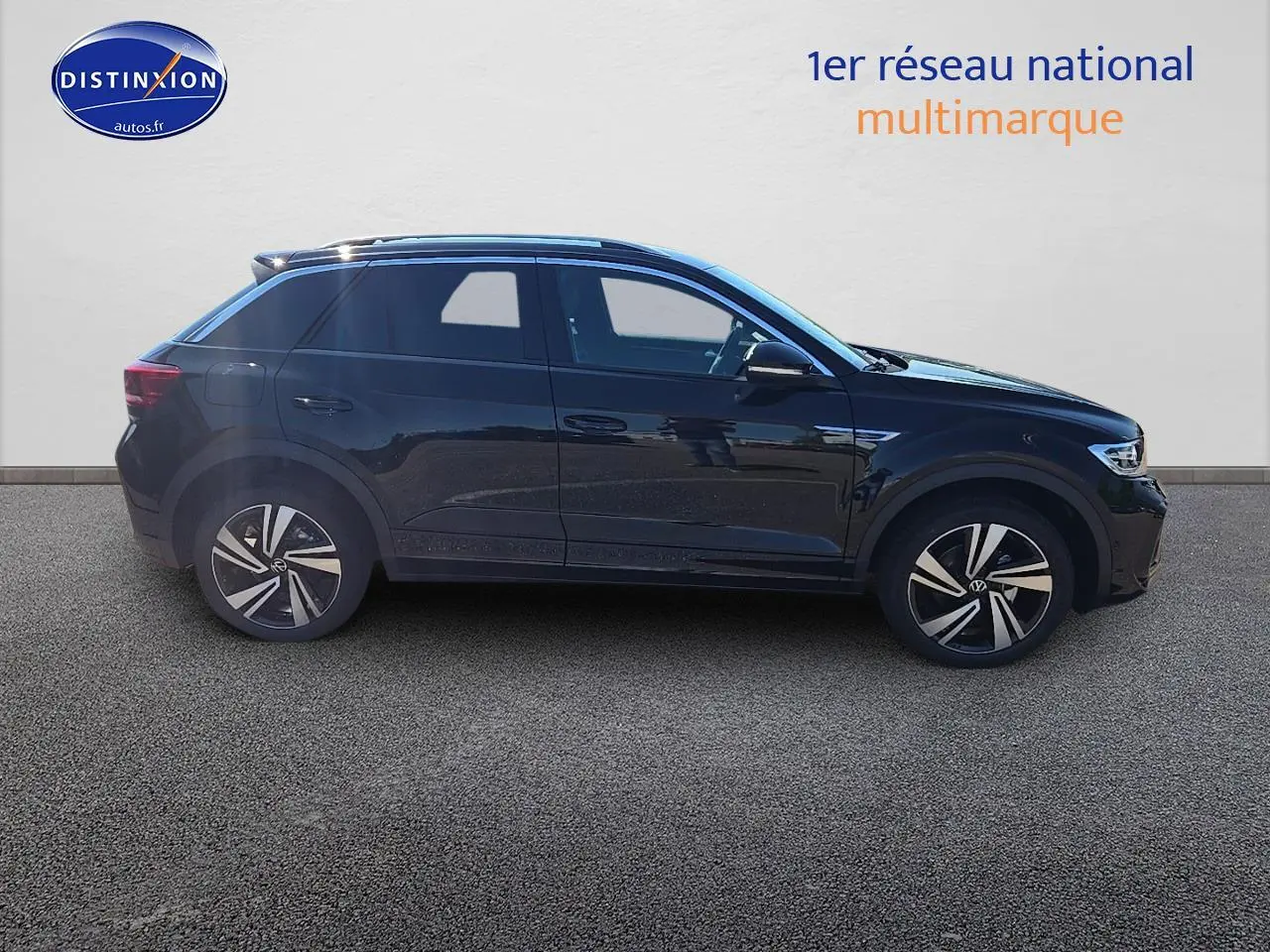 Vue de profil côté gauche d'un Volkswagen T-Roc noir perle avec jantes alliage 18 pouces Nevada noir et barres de toit argentées.