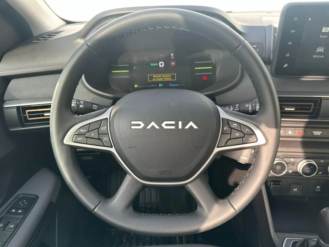 Vue rapprochée du volant noir de la Dacia Jogger 2025 avec commandes intégrées et tableau de bord numérique.