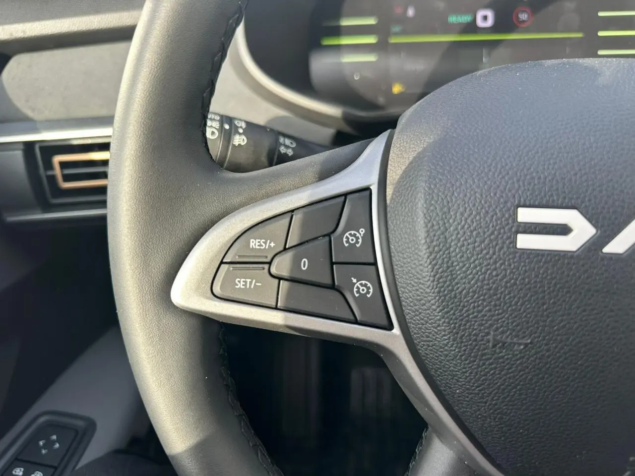 Gros plan sur le volant noir du Dacia Jogger 2025, montrant les commandes de régulateur de vitesse côté gauche.