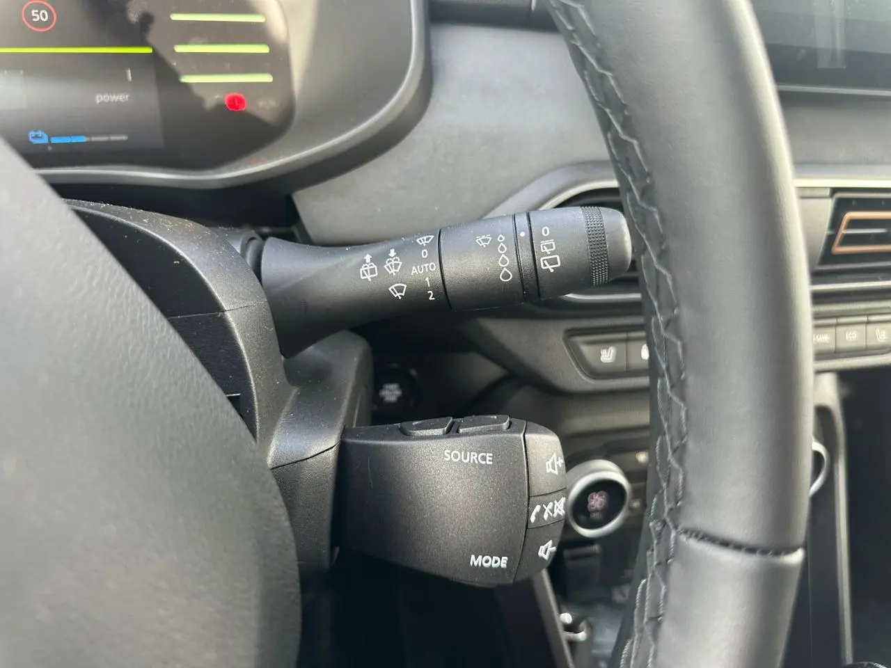 Gros plan sur la commande au volant et le commodo d'essuie-glace du DACIA JOGGER kaki, intérieur noir et détails fonctionnels visibles.