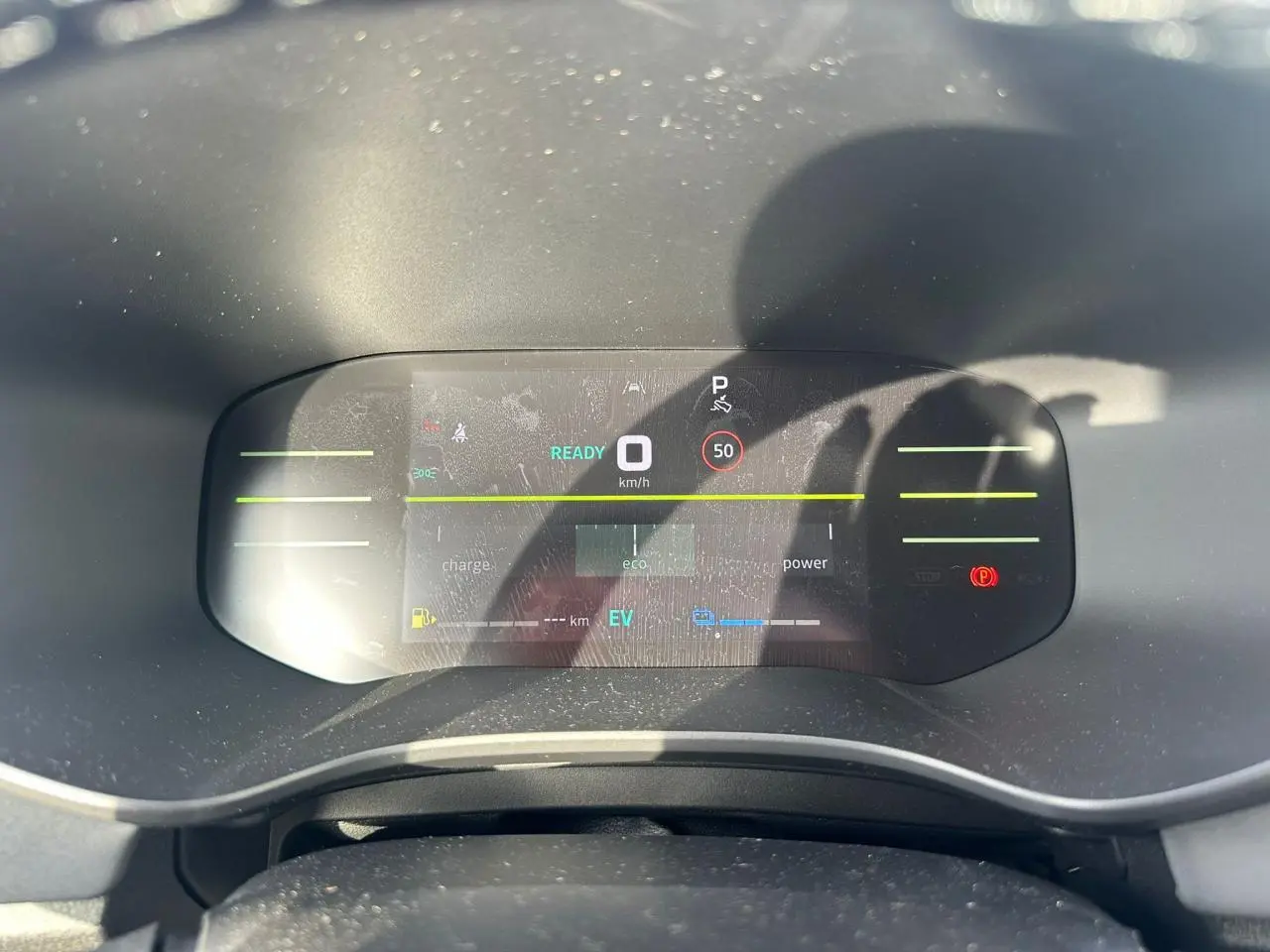 Vue rapprochée du tableau de bord numérique du Dacia Jogger hybride, affichant la vitesse à 0 km/h et indicateurs eco et EV.