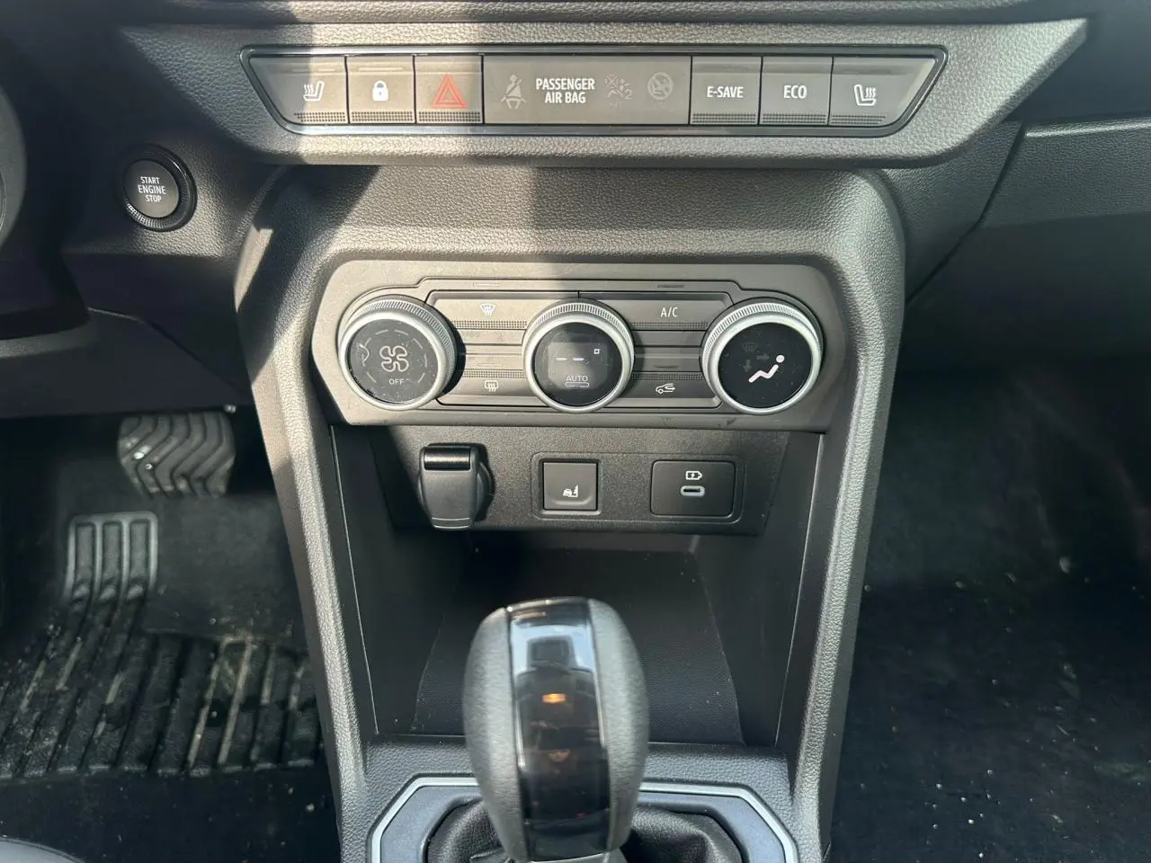 Vue rapprochée de la console centrale du Dacia Jogger kaki, avec commandes climatisation et levier de boîte automatique.