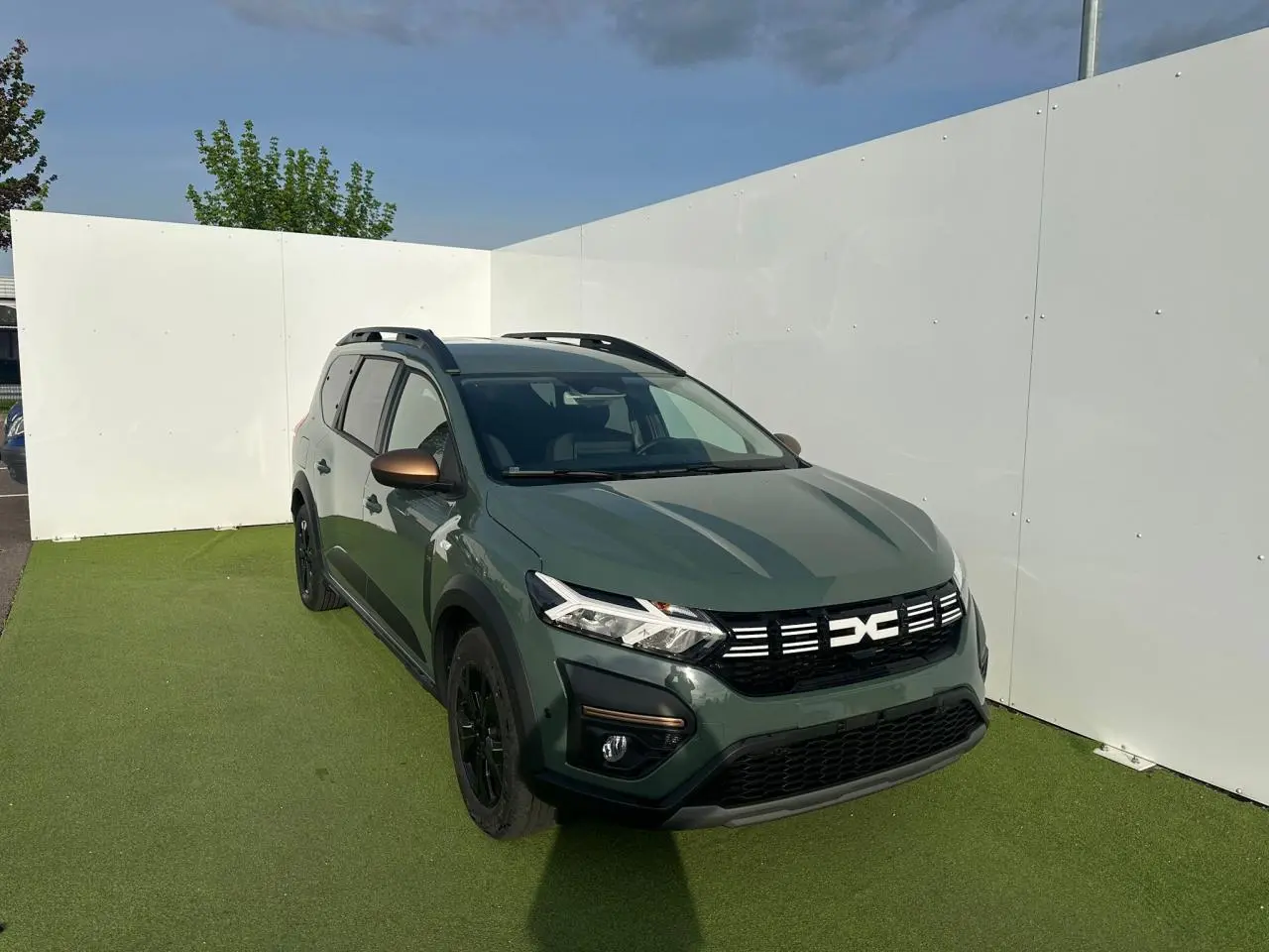 Vue 3/4 avant droite du Dacia Jogger kaki lichen avec calandre noire et rétroviseurs brun cuivré.