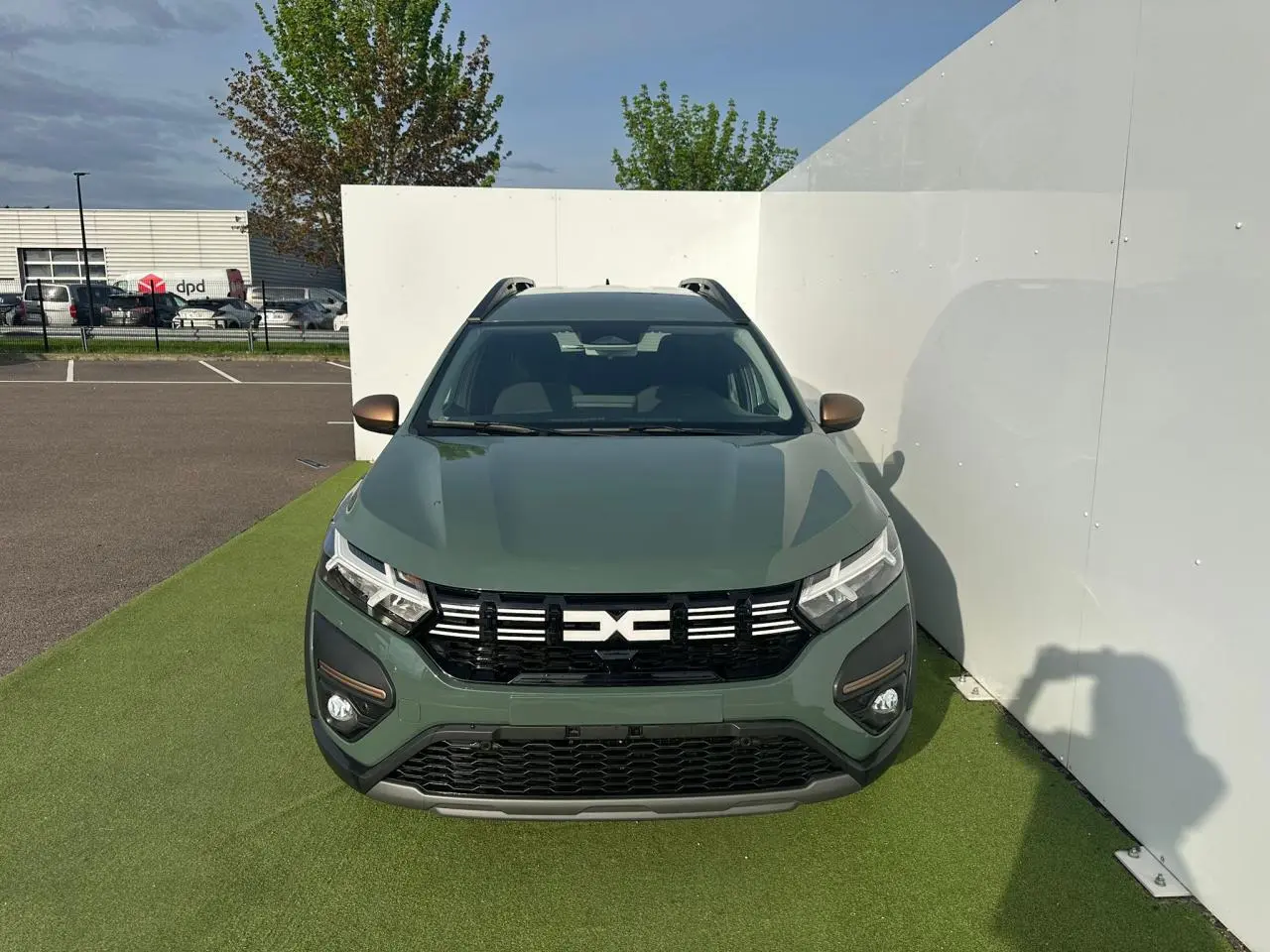 Vue avant du Dacia Jogger 2025 en kaki lichen métal avec calandre noire et barres de toit visibles.