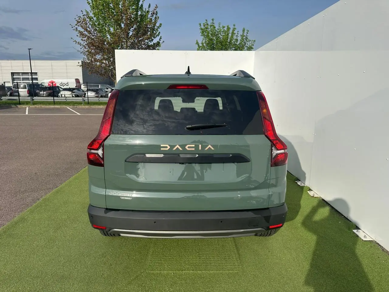 Vue arrière d'un Dacia Jogger hybride 2025 en kaki lichen avec logo blanc et feux LED verticaux distinctifs.