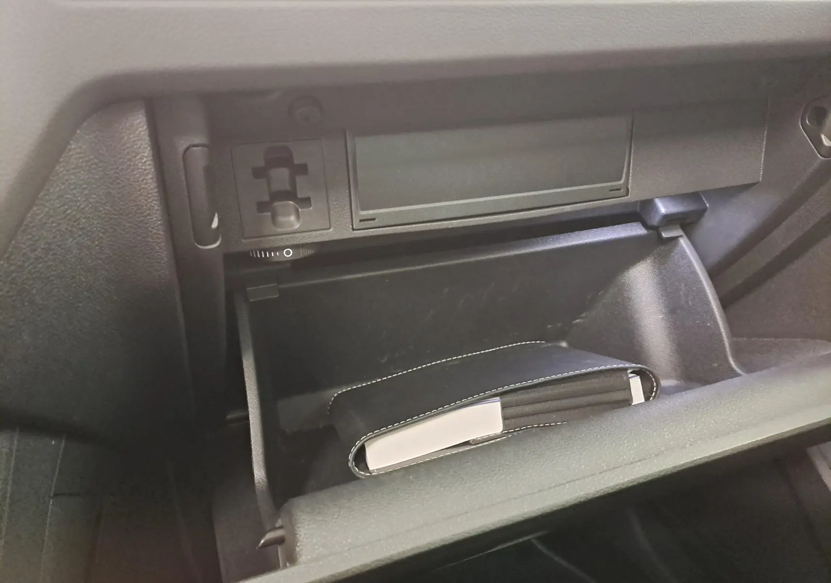 Gant de boîte à gants ouvert montrant un carnet noir avec surpiqûres blanches dans un Volkswagen Tiguan 2023.
