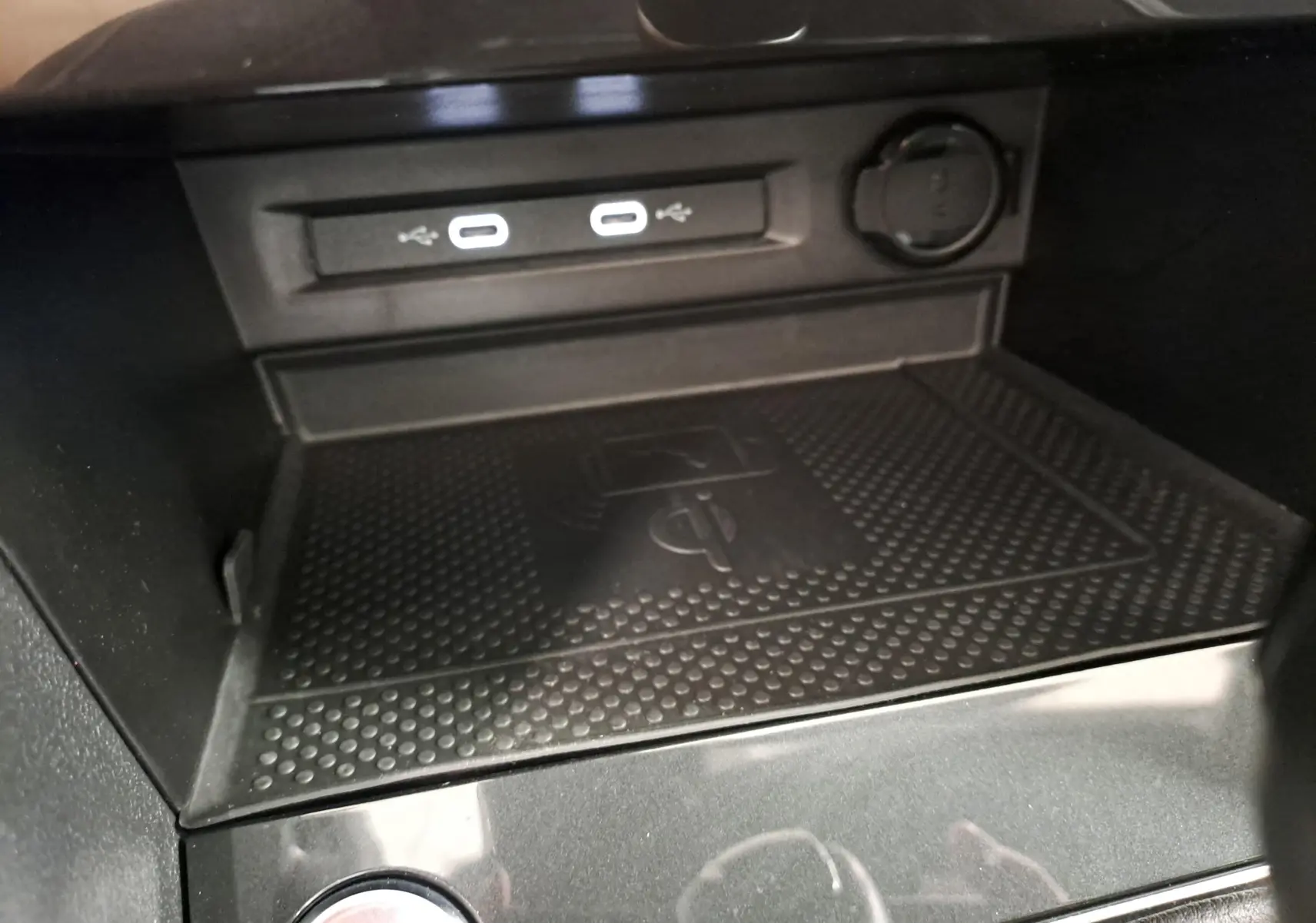 Gros plan sur la console centrale noire du Volkswagen Tiguan 2023, montrant les ports USB-C et le chargeur sans fil.