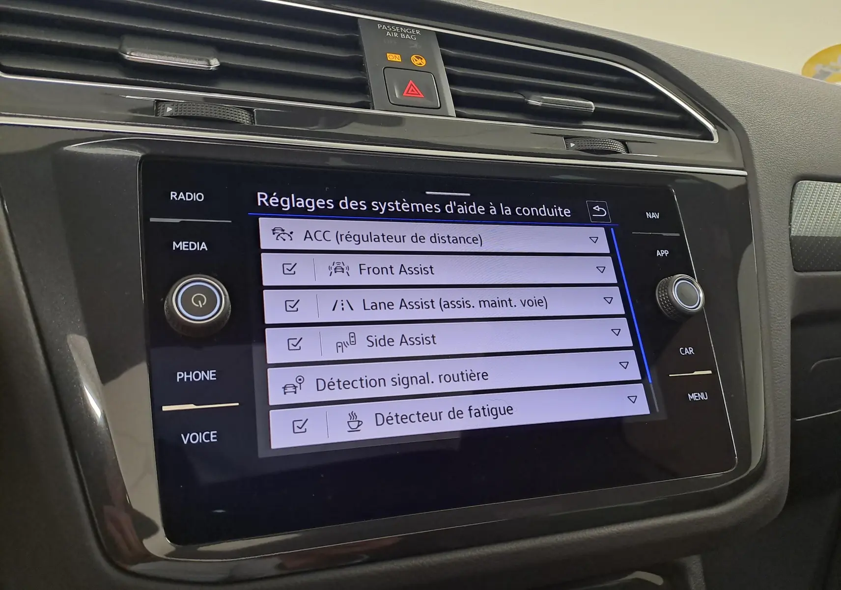 Écran tactile central du Volkswagen Tiguan 2023 affichant les réglages des aides à la conduite, intérieur noir.