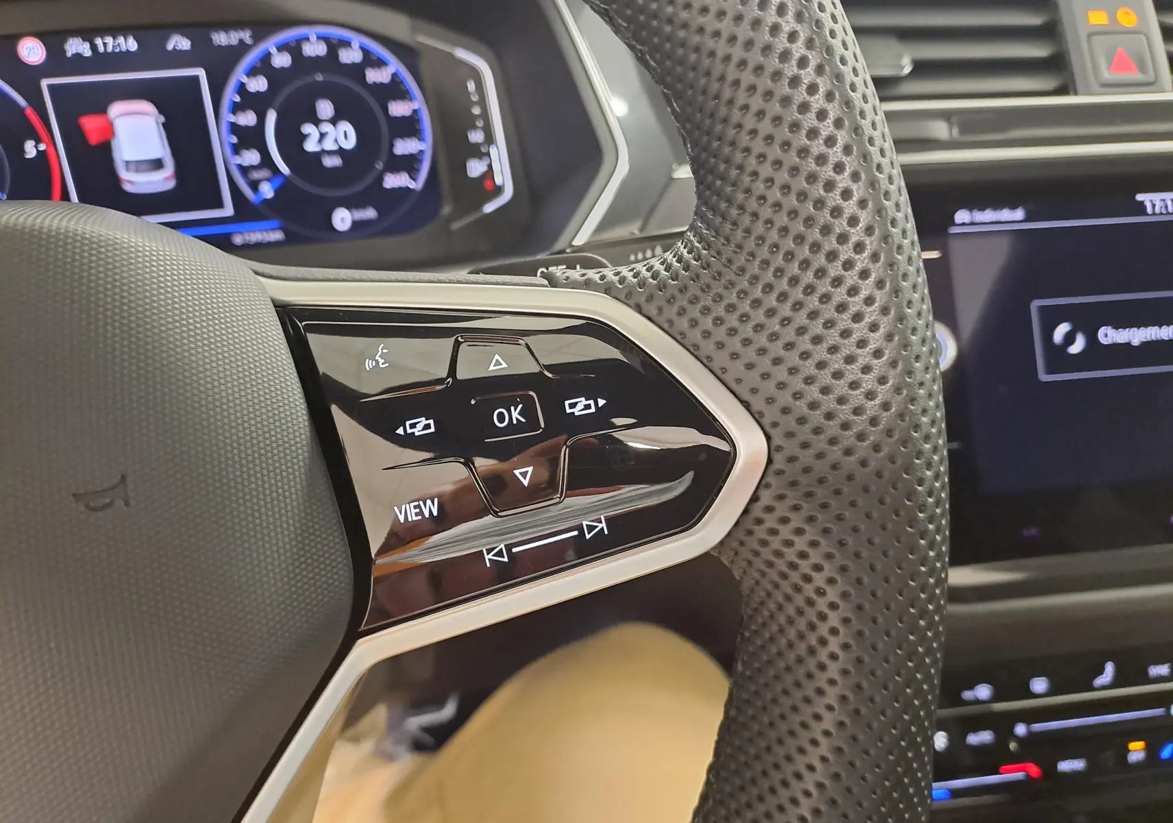 Gros plan sur le volant perforé côté gauche du Volkswagen Tiguan blanc avec commandes tactiles et tableau de bord digital.