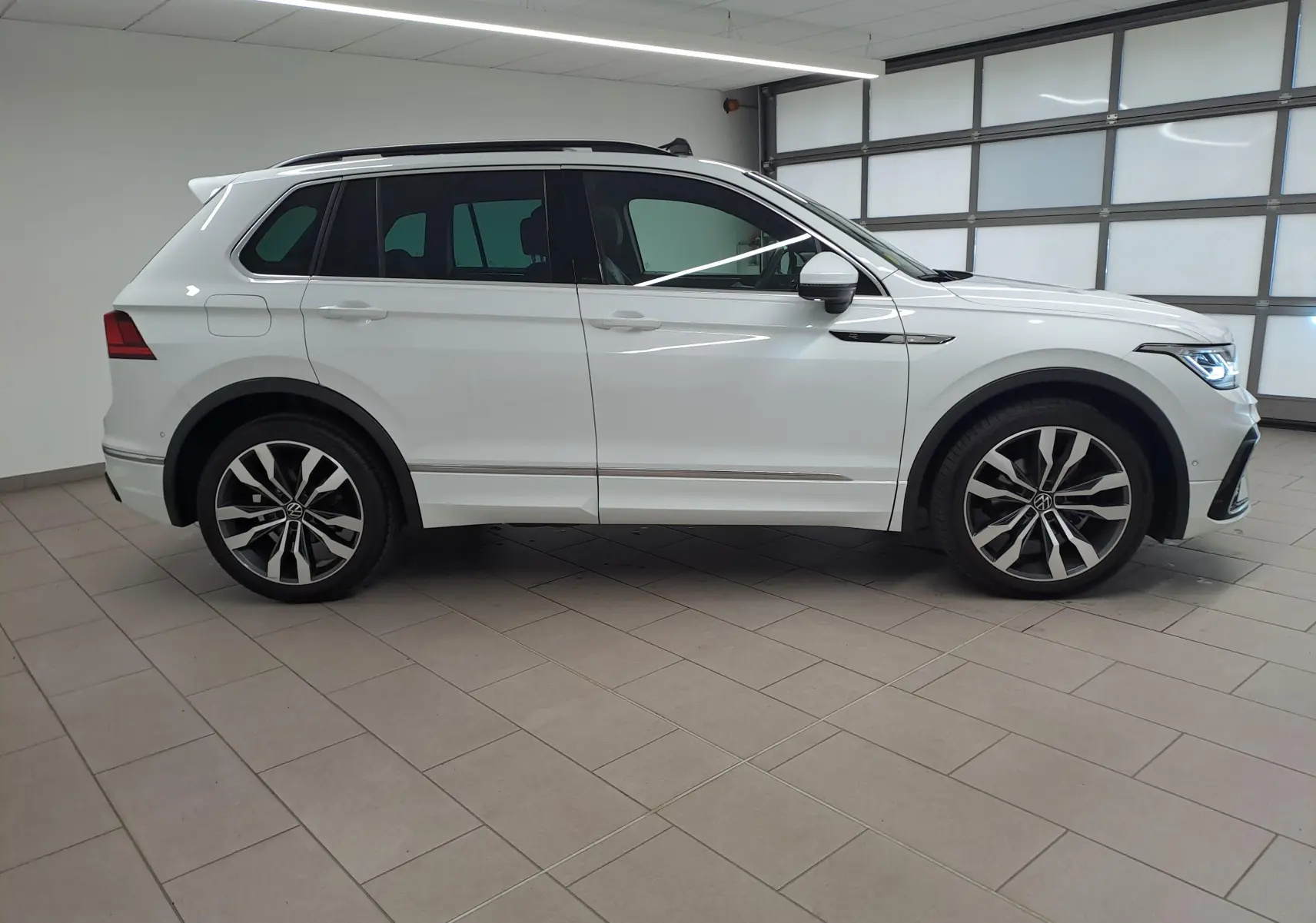 Profil droit du Volkswagen Tiguan blanc pur 2023 avec jantes alliage 20'' Suzuka et toit ouvrant panoramique.