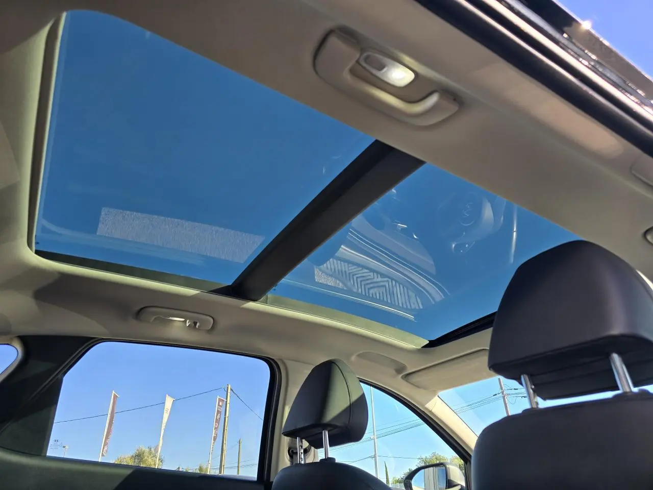 Vue intérieure du toit ouvrant panoramique du Hyundai Tucson noir Phantom Metal, avec ciel bleu visible à travers le verre.