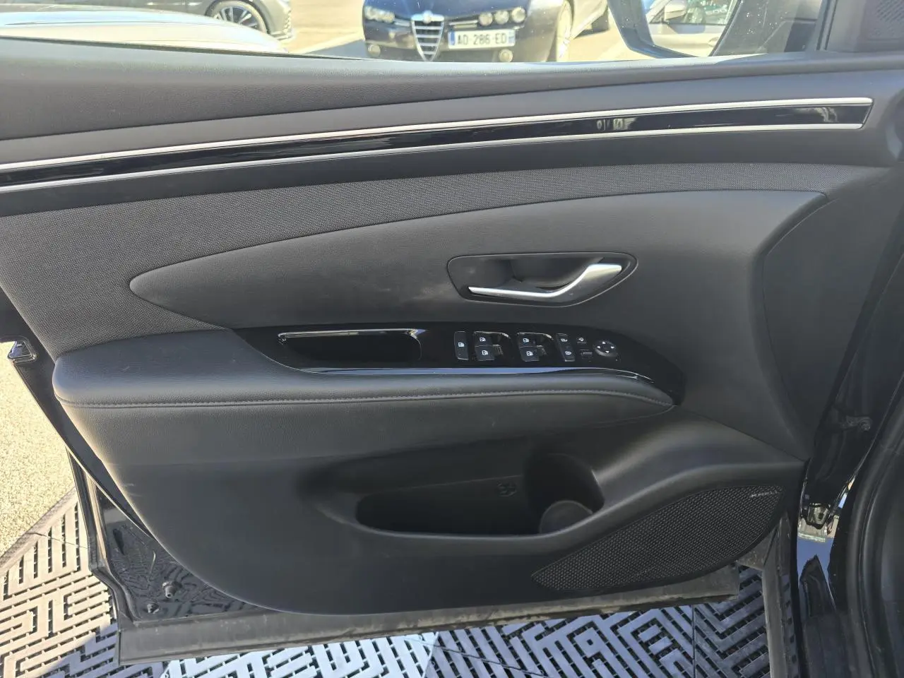 Vue intérieure du panneau de porte avant gauche noir avec commandes électriques et haut-parleur Bose sur Hyundai Tucson 2021.