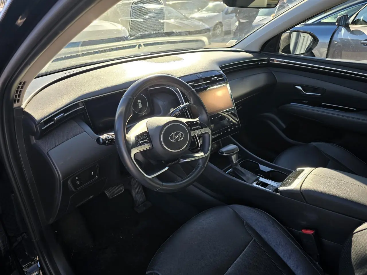 Vue intérieure côté conducteur du Hyundai Tucson noir Phantom Metal 2021, avec tableau de bord moderne et écran tactile central.