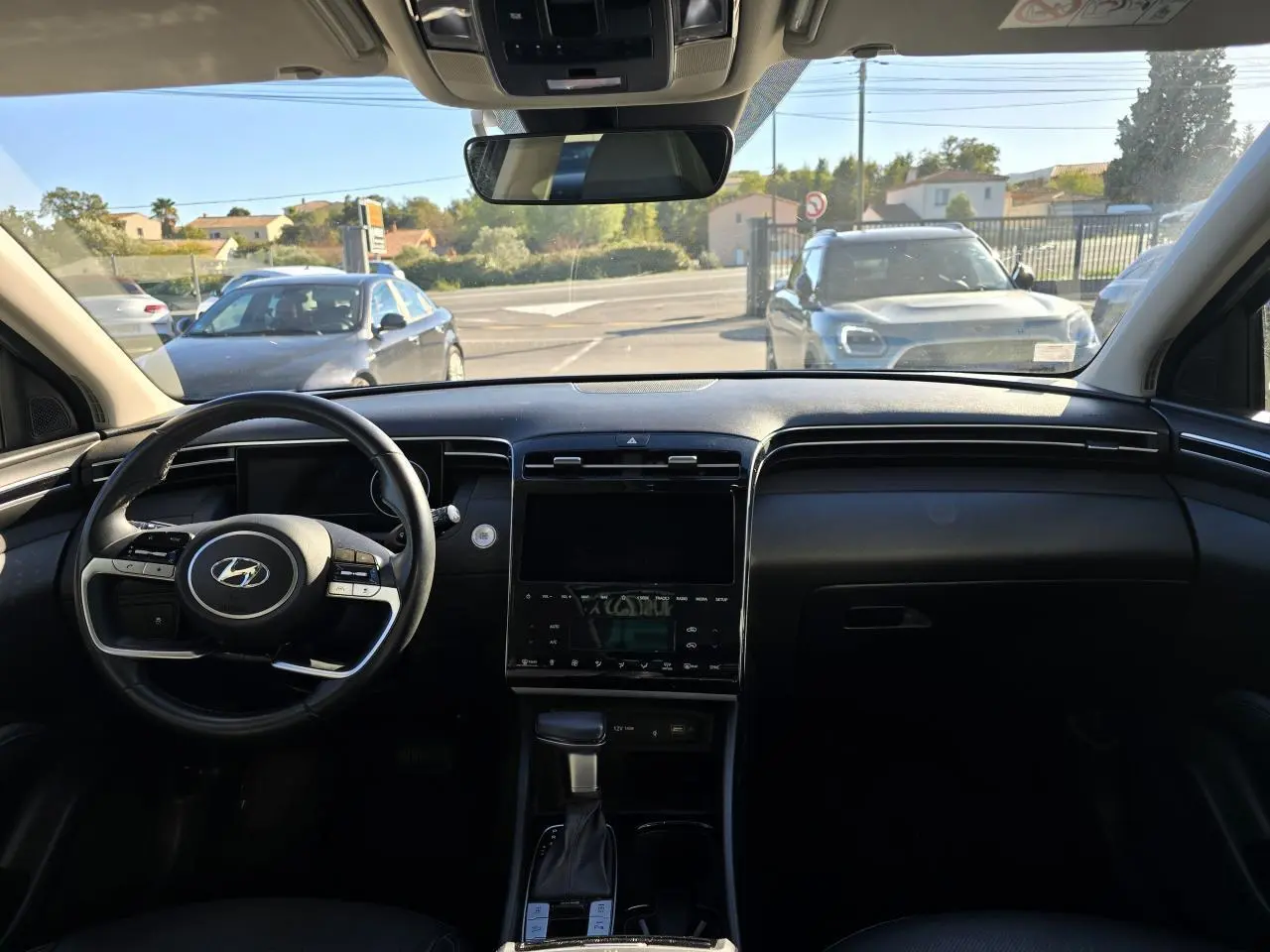Vue intérieure avant du Hyundai Tucson noir Phantom Metal 2021, mettant en valeur le tableau de bord et le volant multifonction.