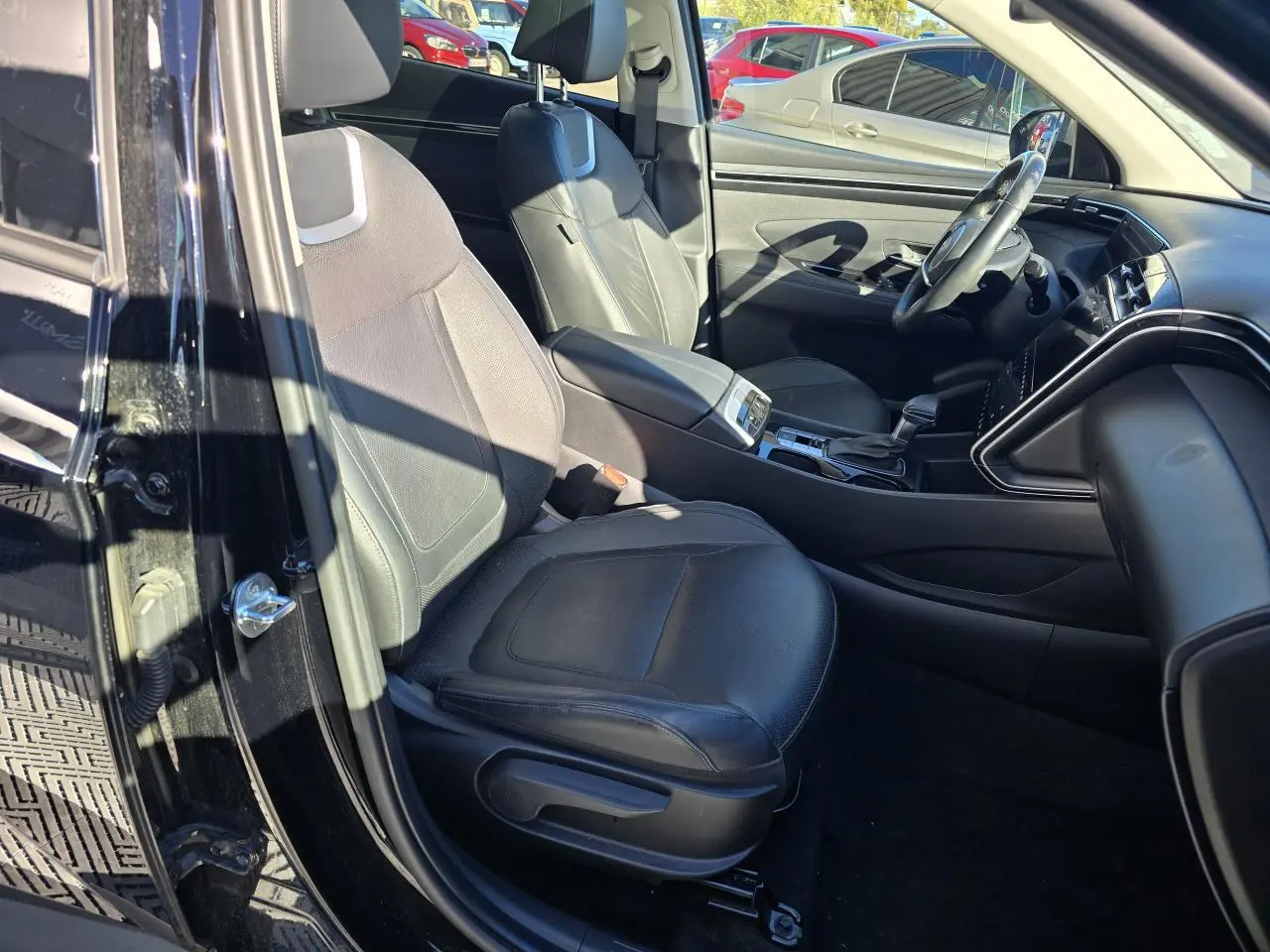 Vue intérieure côté gauche du Hyundai Tucson noir Phantom Metal 2021, mettant en valeur les sièges cuir noirs et la console centrale.