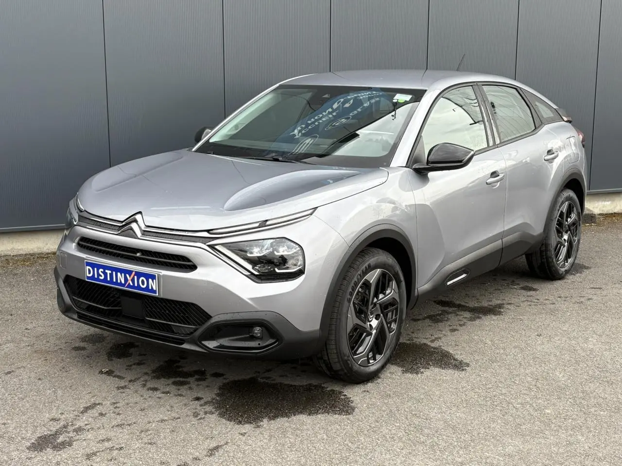 Citroën C4 gris acier vue 3/4 avant droit, avec jantes alliage noires et phares LED distinctifs.