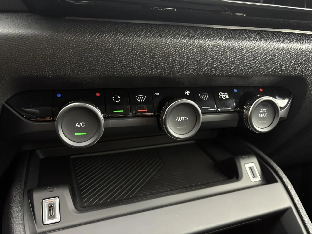 Gros plan sur la console centrale de la Citroën C4 2024, montrant les commandes de climatisation automatique et une prise USB.