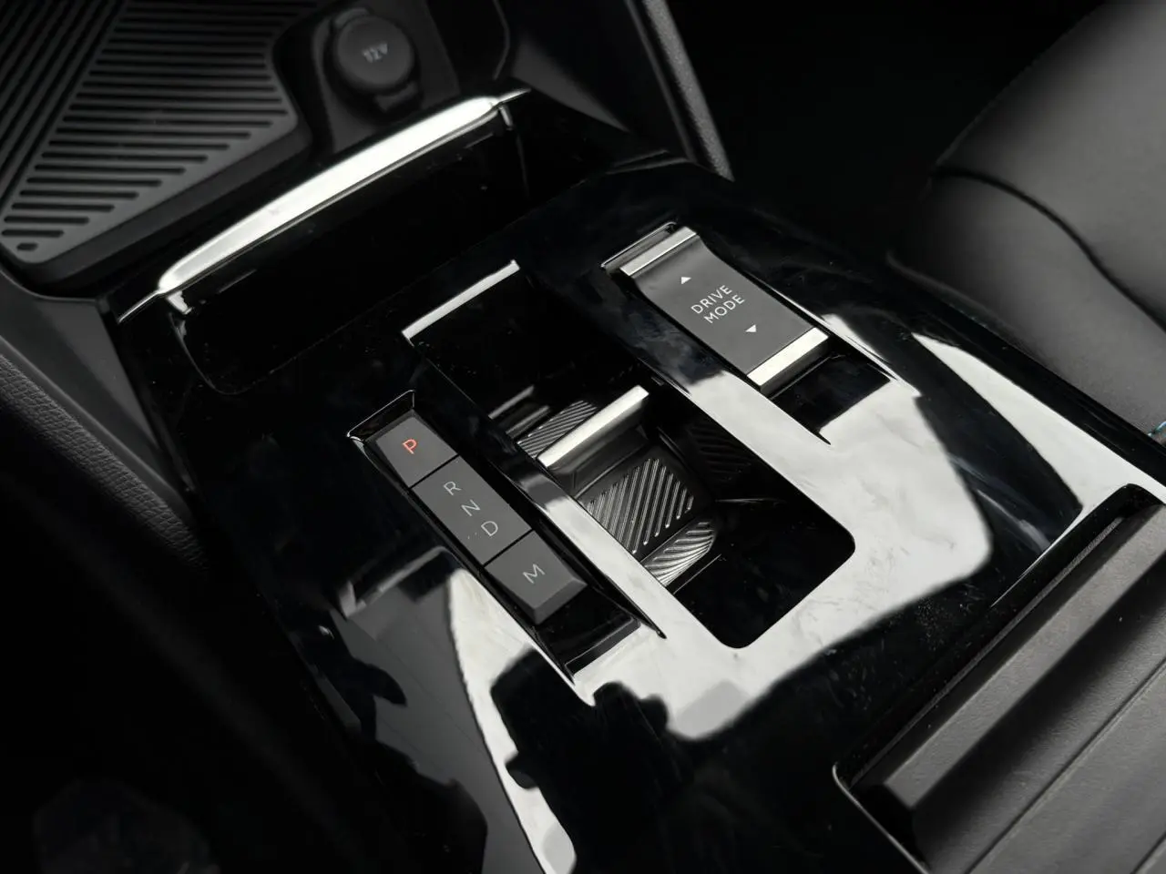 Gros plan sur la console centrale noire brillante de la Citroën C4 1.5 BlueHDi 130 avec sélecteur de boîte auto et commande Drive Mode.