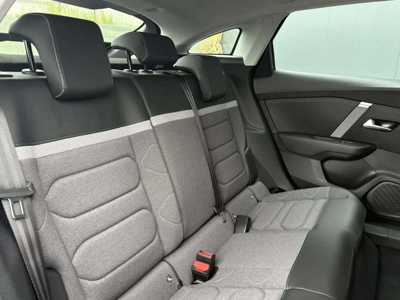 Vue intérieure de la banquette arrière grise et noire de la Citroën C4 2024, côté droit avec ceinture et appuie-têtes visibles.