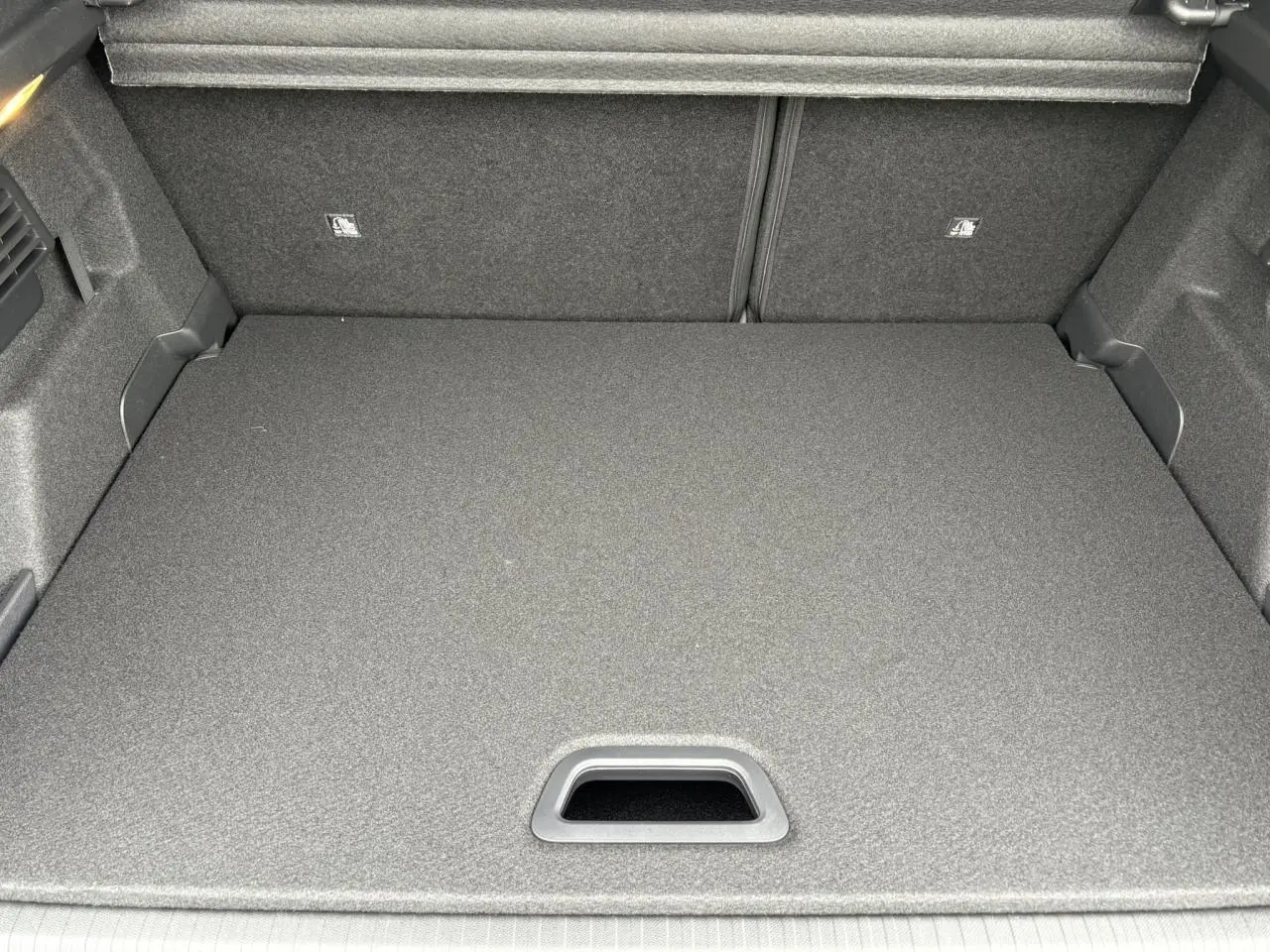 Coffre ouvert vu de dessus de la Citroën C4 gris acier, montrant la surface de chargement plate et le cache-bagages.