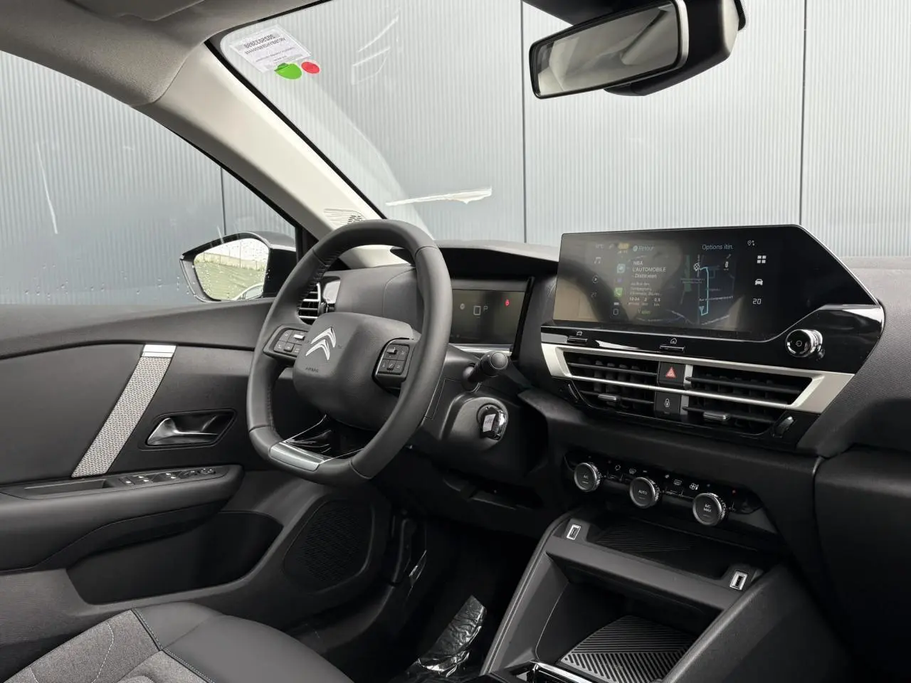 Intérieur de la Citroën C4 2024 vu côté conducteur, tableau de bord moderne avec écran tactile et volant cuir noir.