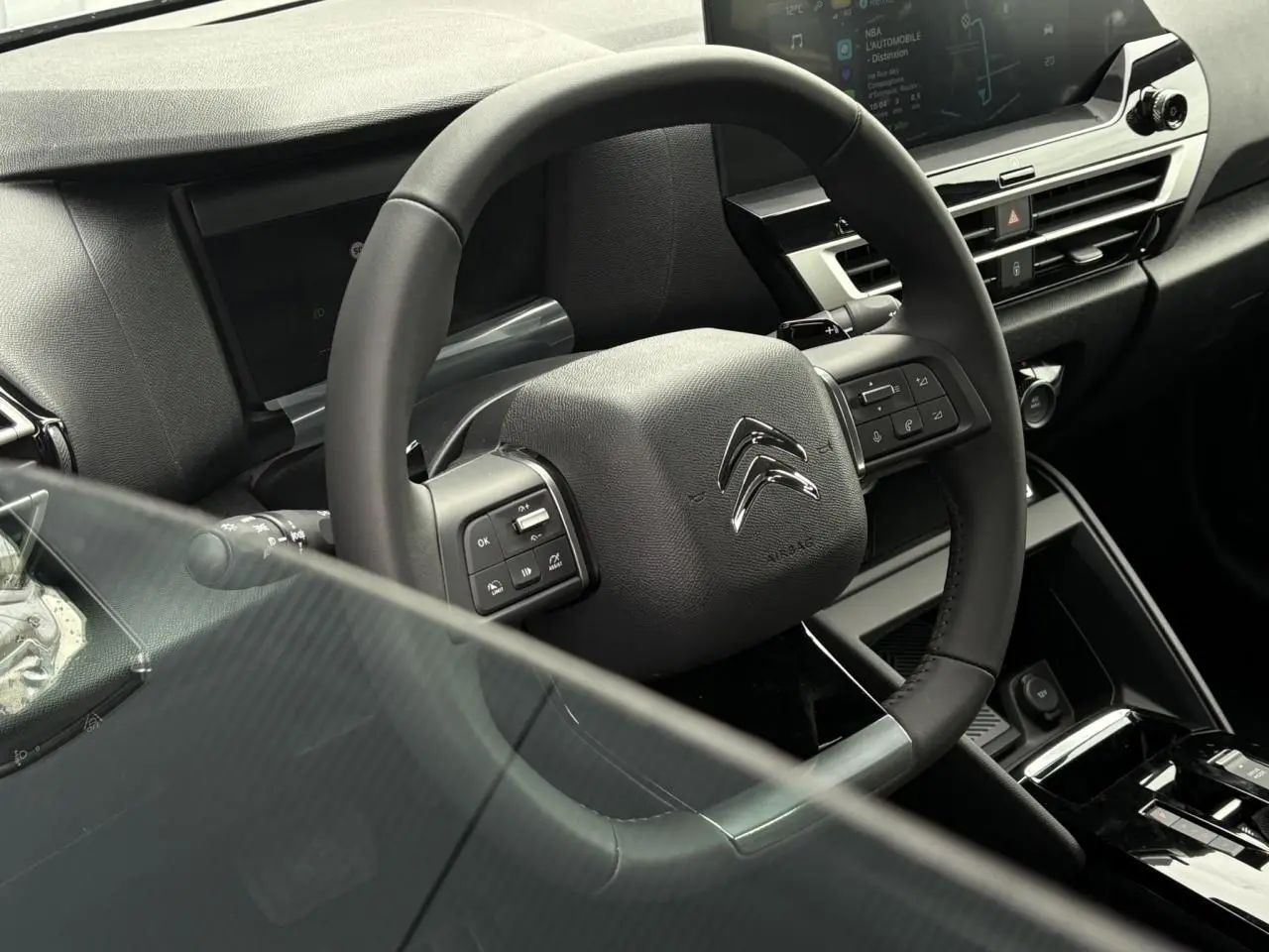 Vue rapprochée du volant cuir de la Citroën C4 2024 avec commandes intégrées et tableau de bord numérique.