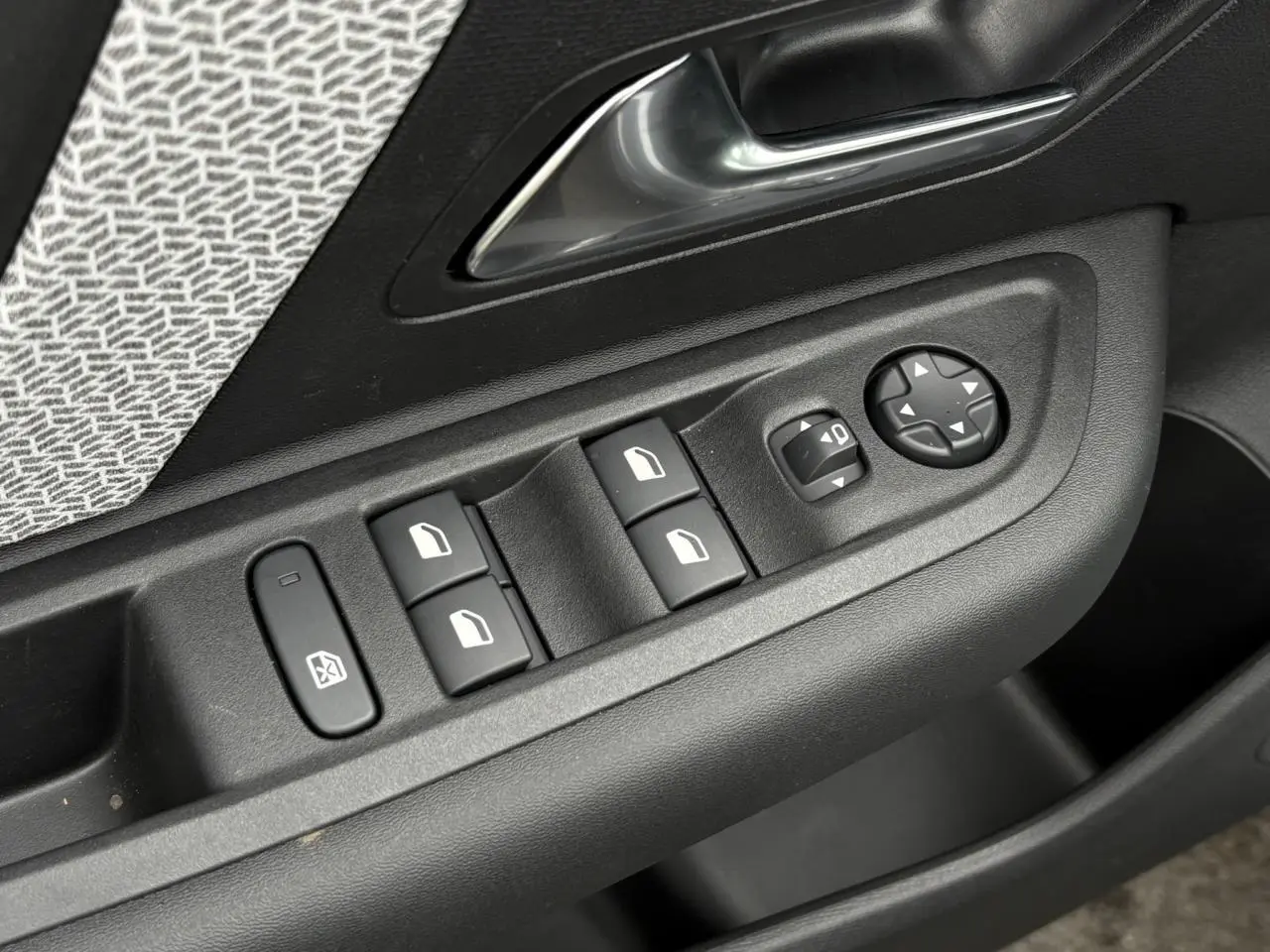 Gros plan sur les commandes de lève-vitres et réglages des rétroviseurs côté conducteur d’une Citroën C4 gris acier.