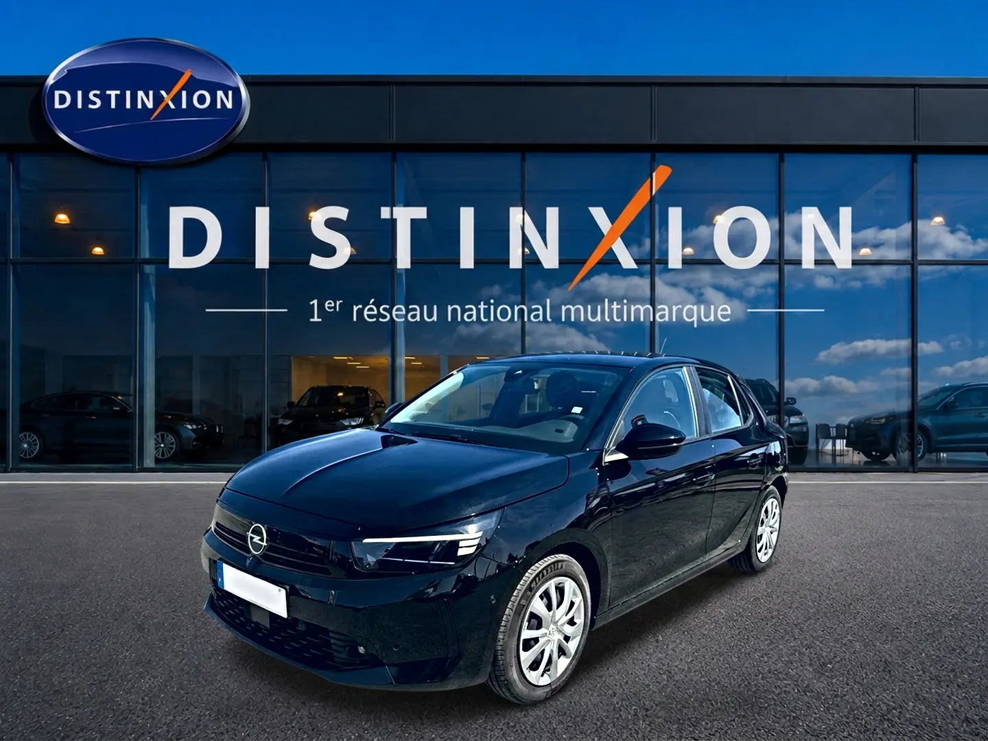 Opel Corsa noire vue en 3/4 avant droit, avec jantes argentées, devant une vitrine Distinxion.