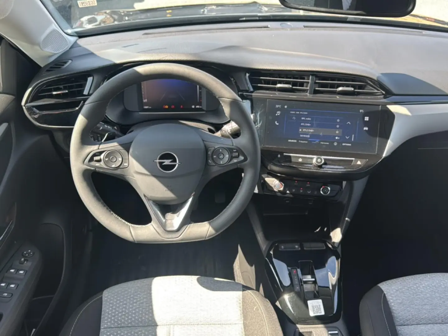 Vue intérieure avant de l’Opel Corsa noire 2025, avec volant multifonction, écran tactile et sièges tissu bicolore.