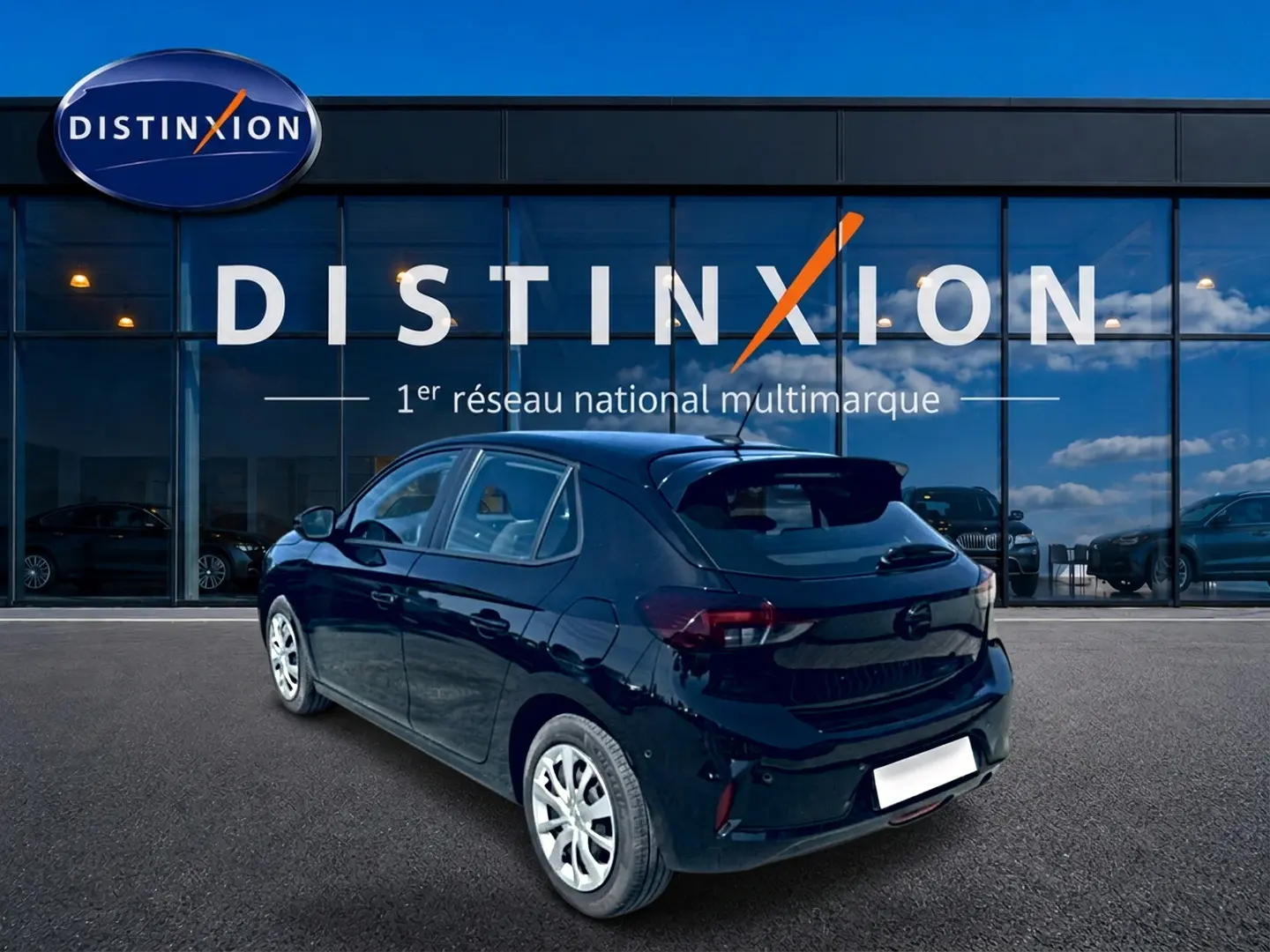 Opel Corsa noire vue 3/4 arrière droit, avec becquet et feux arrière LED, devant vitrine Distinxion.