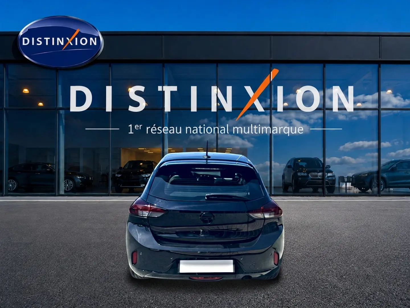 Vue arrière d'une Opel Corsa noire 2025 garée devant une vitrine avec logo Distinxion en arrière-plan.
