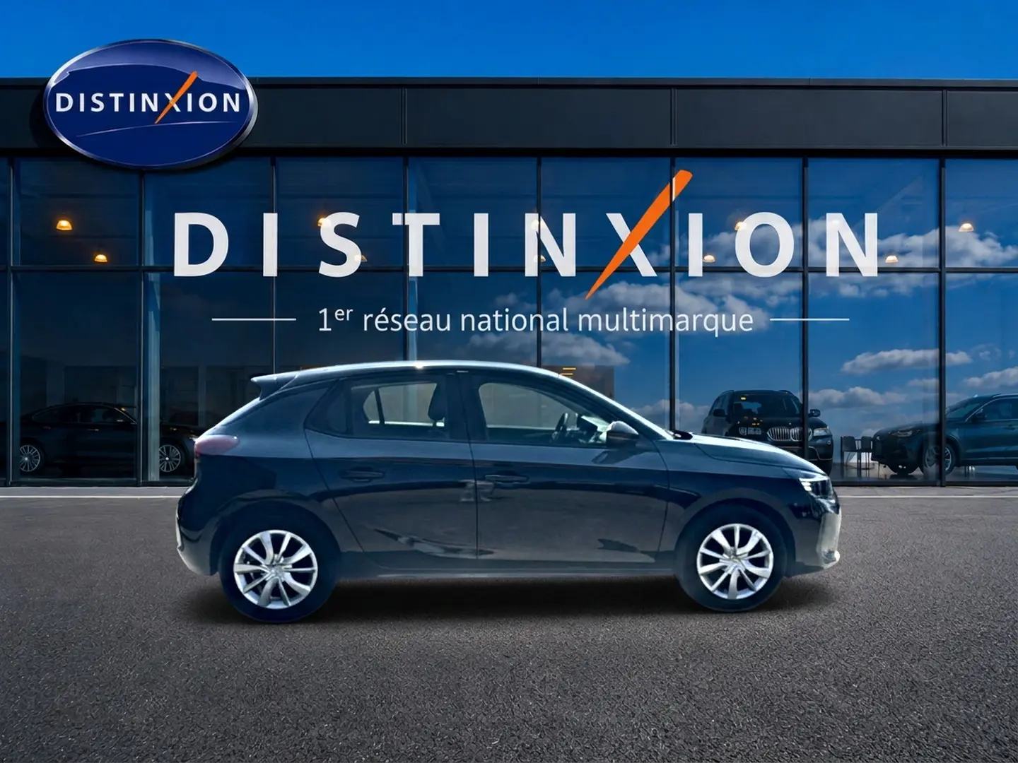 Profil côté gauche d'une Opel Corsa noire 2025 garée devant une vitrine avec logo Distinxion.