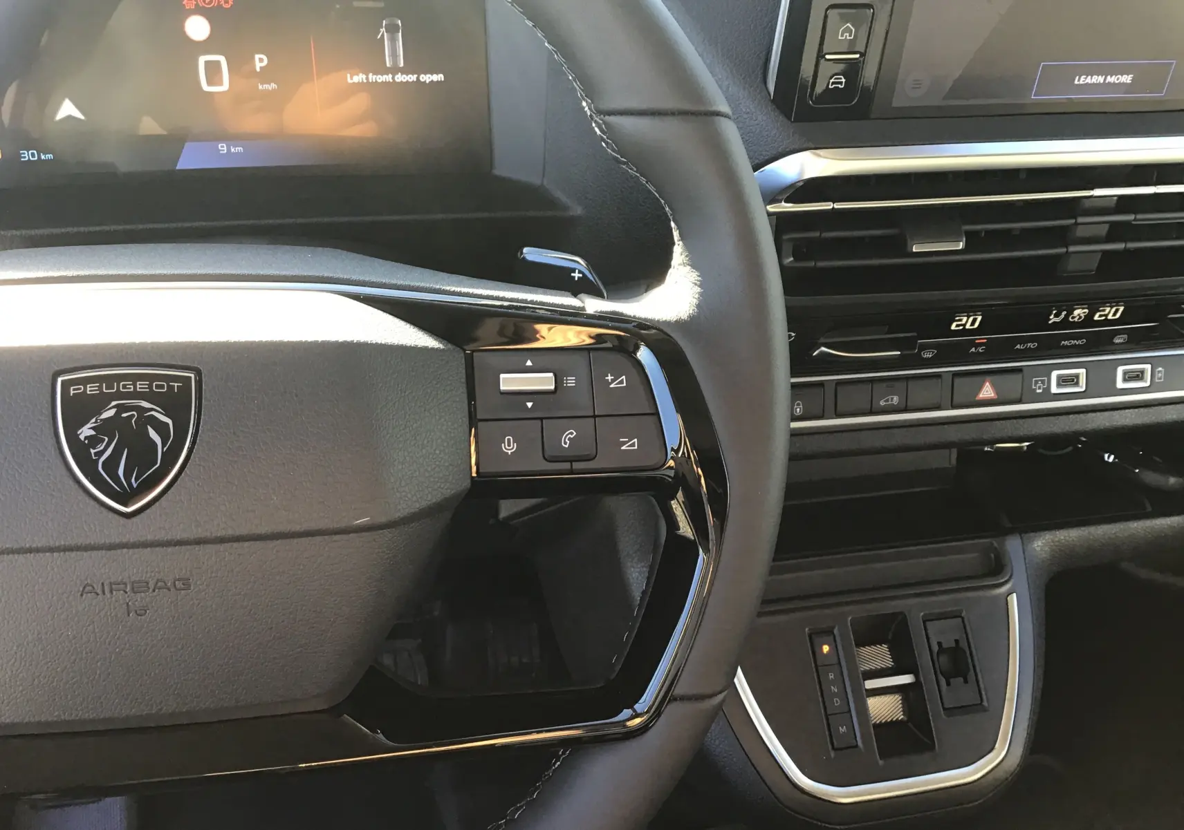 Vue rapprochée du volant Peugeot noir avec commandes intégrées et tableau de bord numérique du Expert Fourgon blanc 2024.