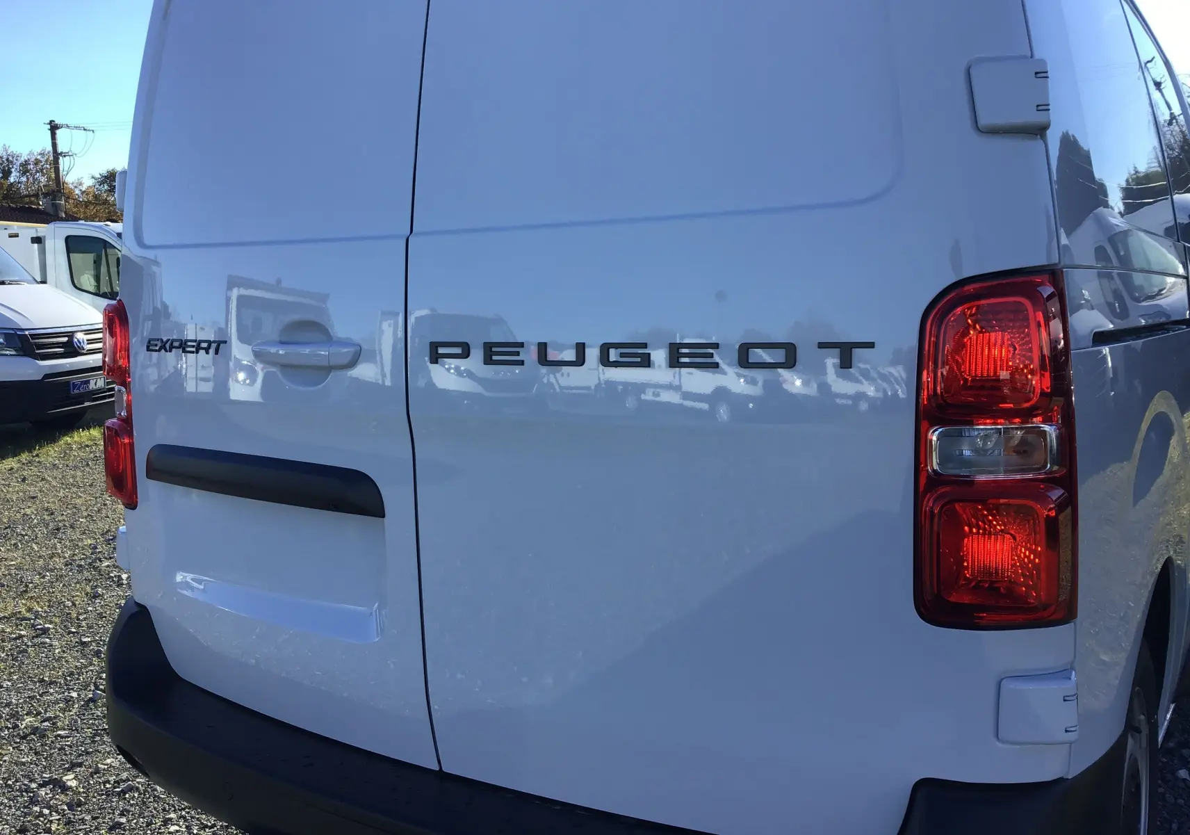 Vue arrière droite d'un Peugeot Expert Fourgon blanc 2024 avec feux rouges et logo distinctif sur porte battante.