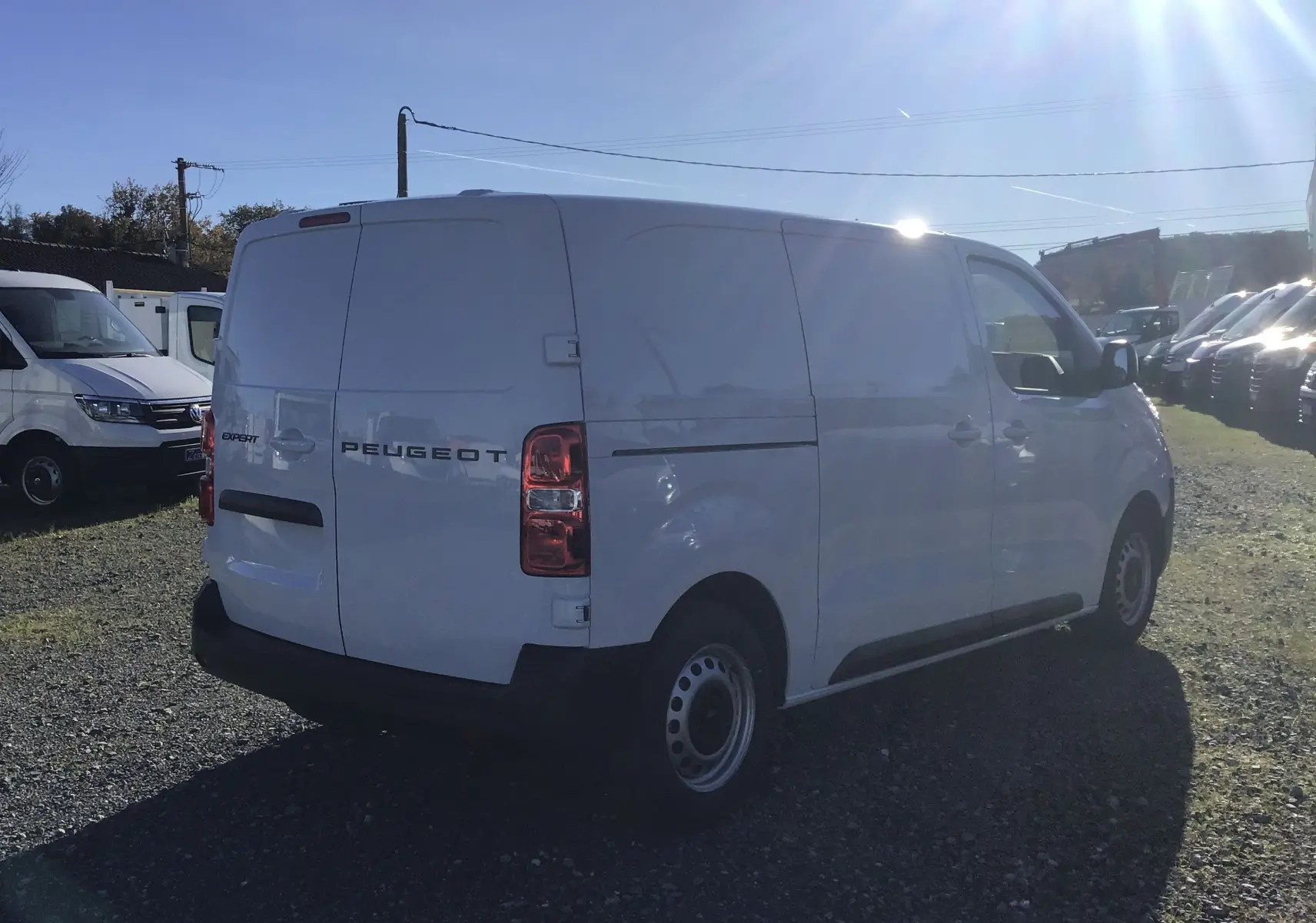Vue 3/4 arrière droite d’un Peugeot Expert Fourgon blanc 2024, avec portes arrière fermées sur un parking extérieur.