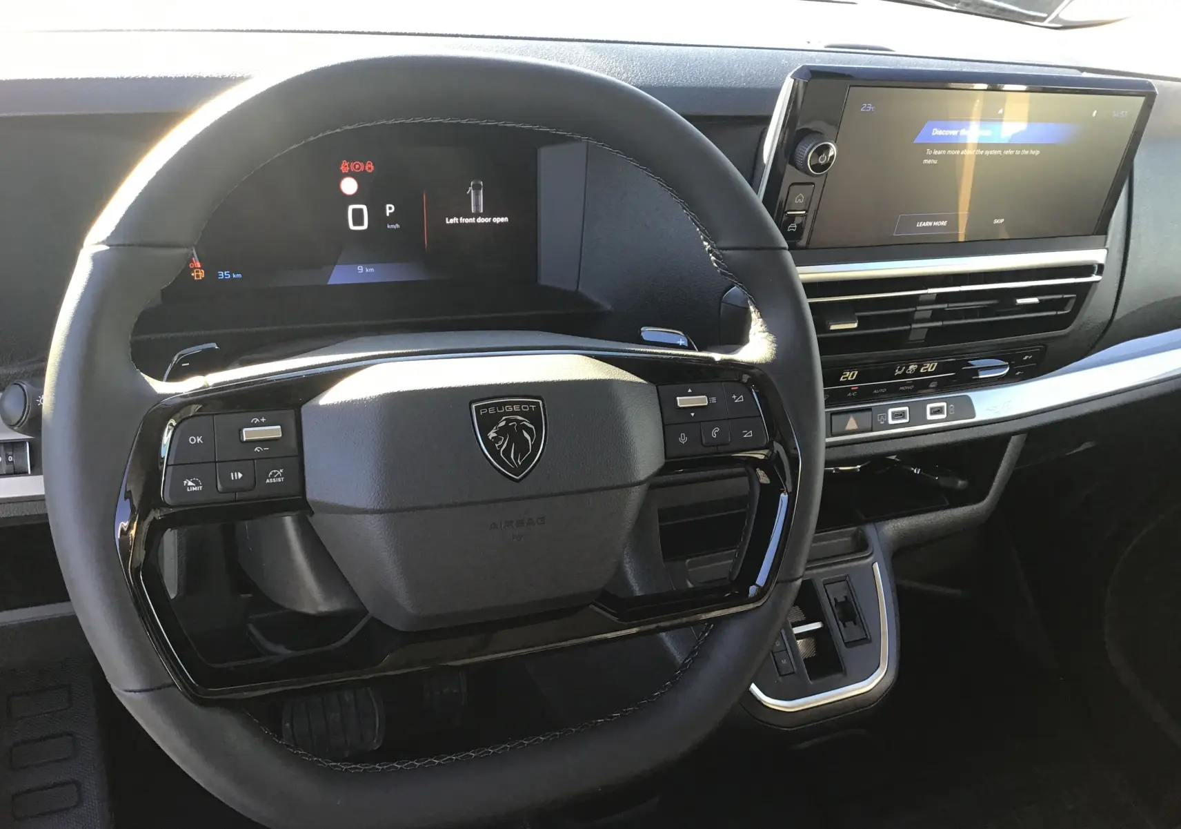 Vue rapprochée du volant noir et du tableau de bord numérique du Peugeot Expert Fourgon blanc 2024 avec écran tactile et commandes intégrées.
