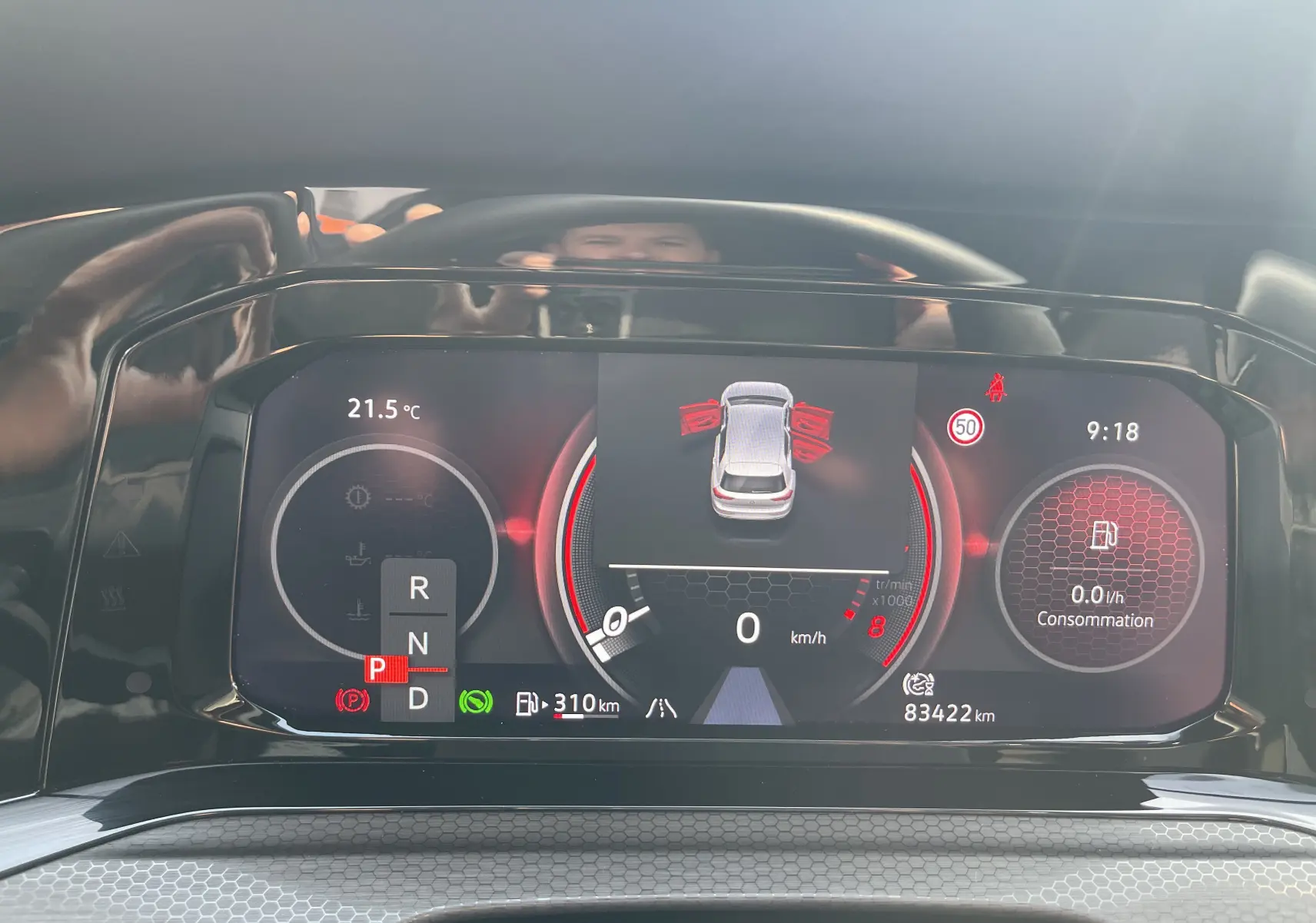 Tableau de bord numérique de la Volkswagen Golf VIII GTI gris, affichant la vitesse à 0 km/h et les portes ouvertes.