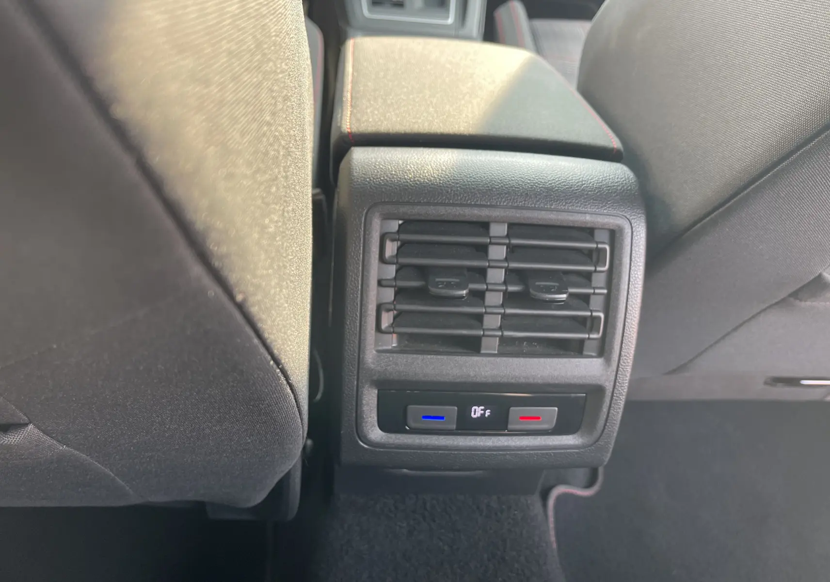 Détail de la console arrière avec bouches d'aération et commandes de climatisation dans une Volkswagen Golf VIII GTI gris.