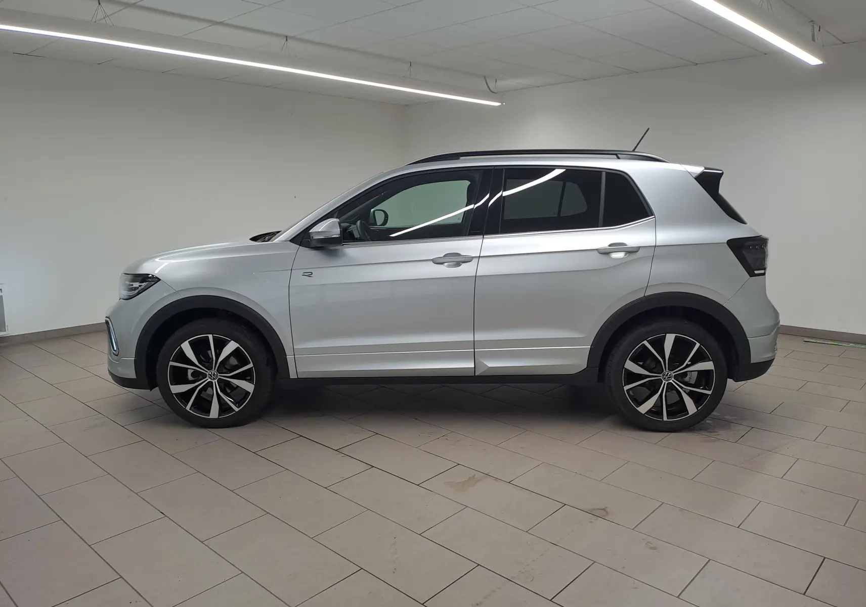 Profil côté gauche d'un Volkswagen T-Cross 2025 argent métallisé avec jantes alliage 18 pouces et finition R-Line.