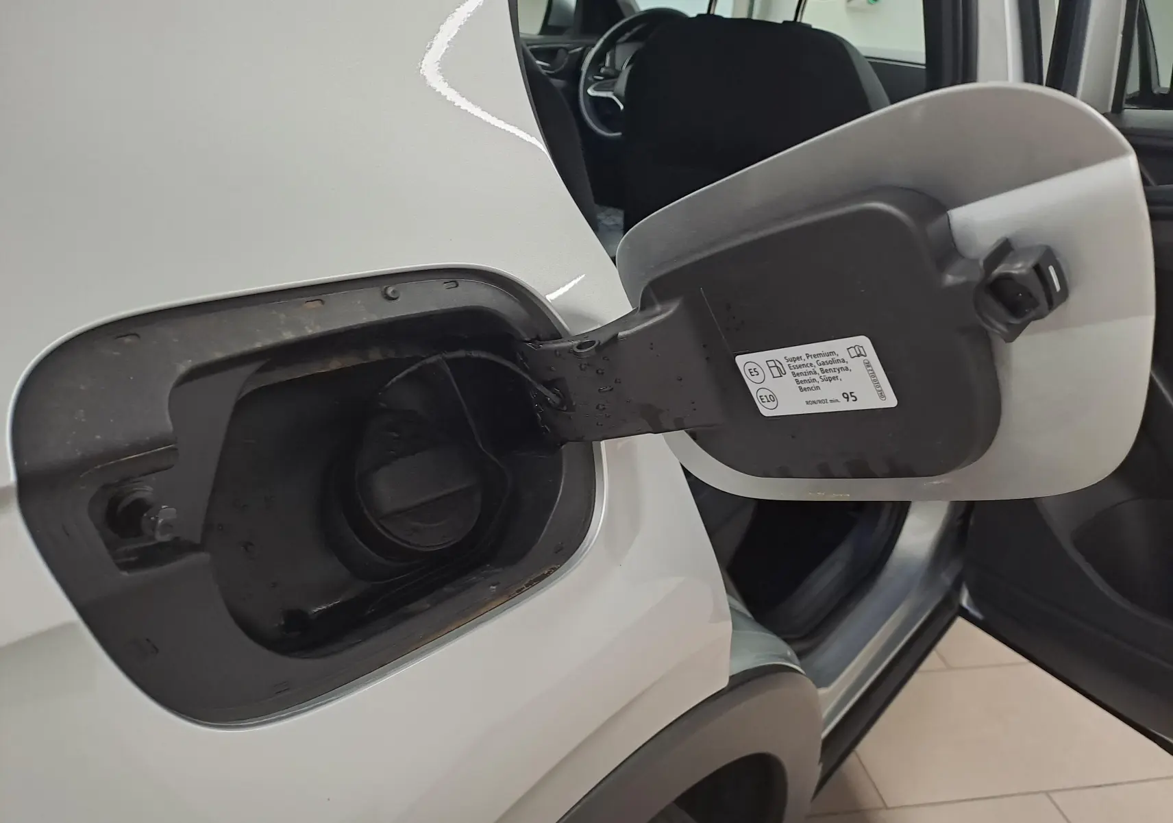 Vue rapprochée de la trappe à carburant ouverte côté gauche d'un Volkswagen T-Cross argent métallisé 2025.